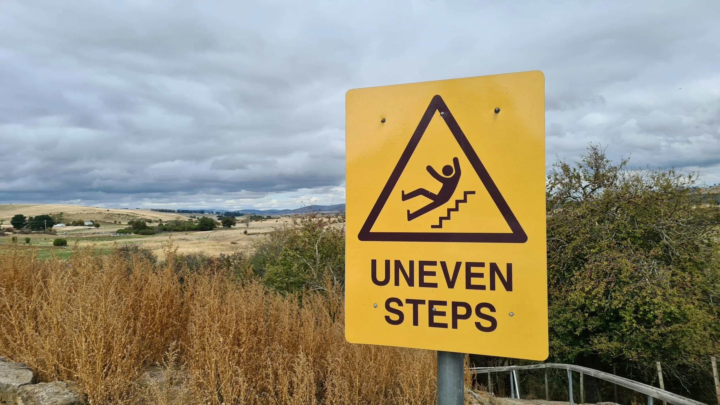 Yellow warning sign indicating uneven steps with a symbol of a person falling.