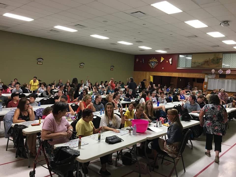 Personnes assises à des tables dans une salle, participant à un événement communautaire ou à un jeu de bingo.