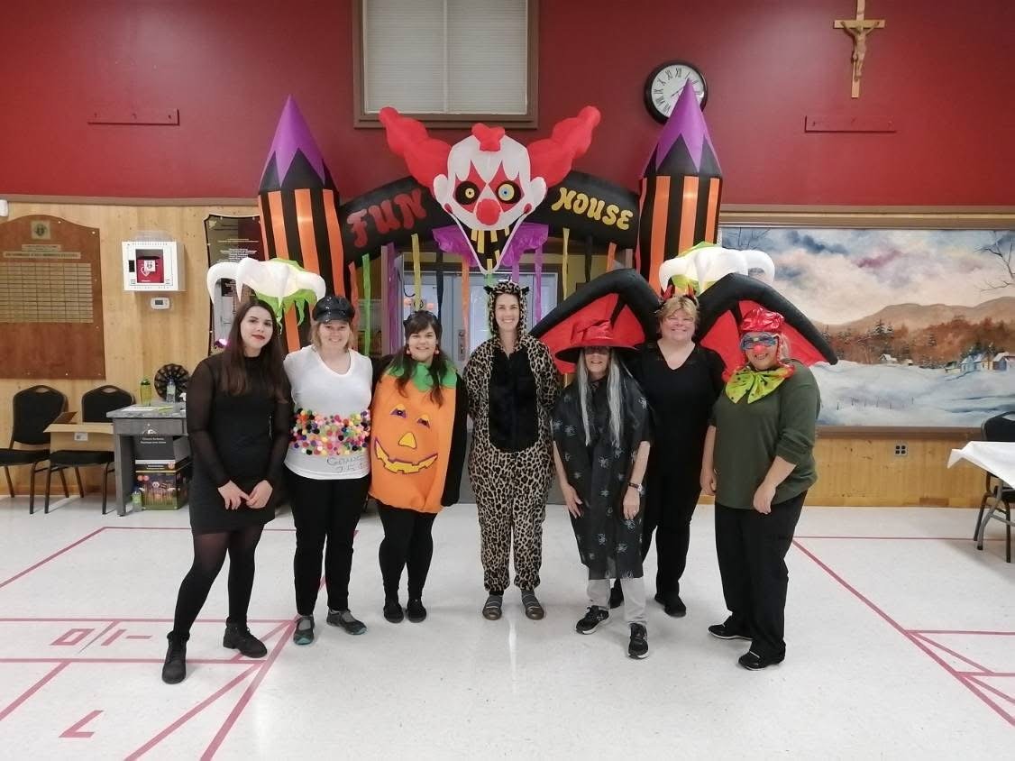 Groupe de personnes déguisées devant une maison hantée colorée.