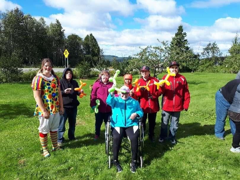 Un groupe de personnes sur une pelouse, l'une en costume de clown, tenant des ballons d'animaux.