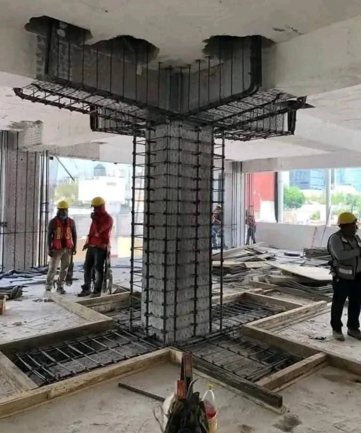 Construction workers in a building with concrete columns and exposed rebar, preparing for concrete pouring.