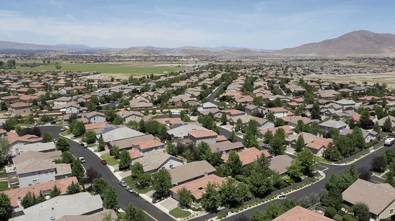 Curti Ranch Aerial view of a suburban neighborhood with houses, trees, and streets, with mountains in the background.