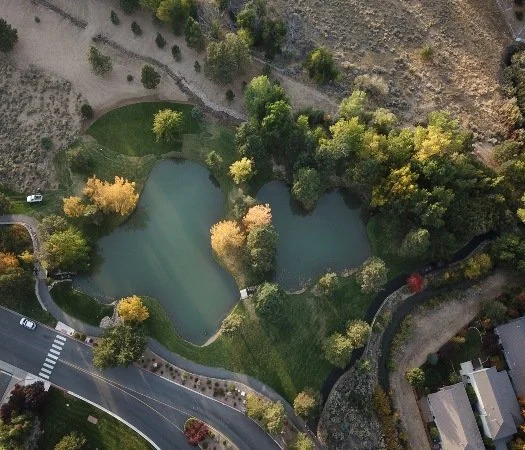 Caughlin Ranch Aerial view of a park with two small lakes, trees, pathways, and surrounding roads and buildings.