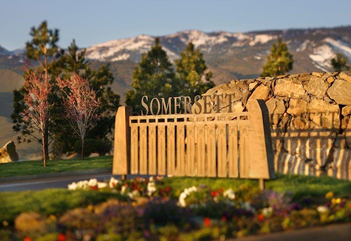 Photo of the Somersett sign at the entrance with mountains and trees in the background and flowers in the foreground.