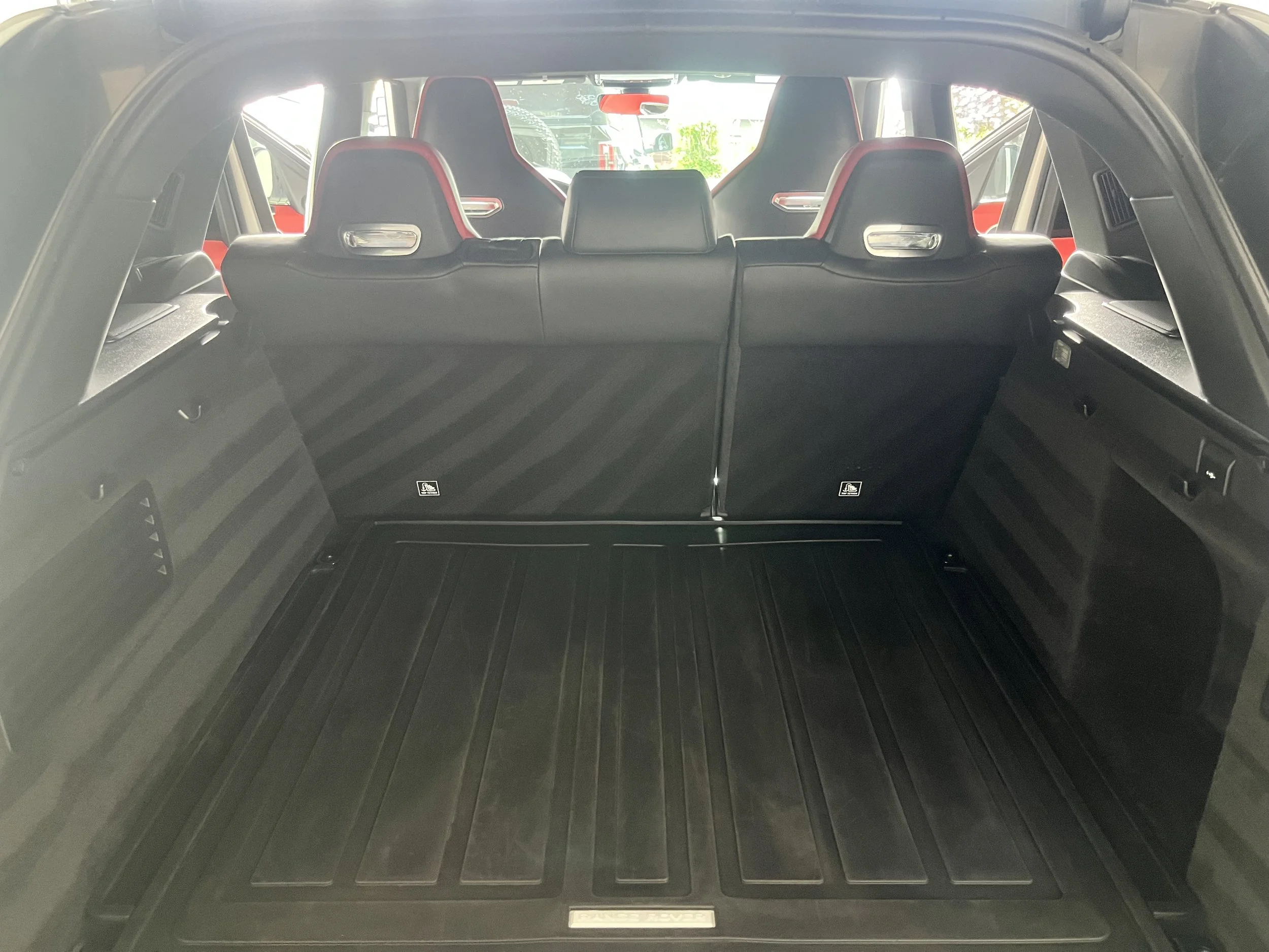 The interior cargo space of an SUV with black cargo lining and rear seats.