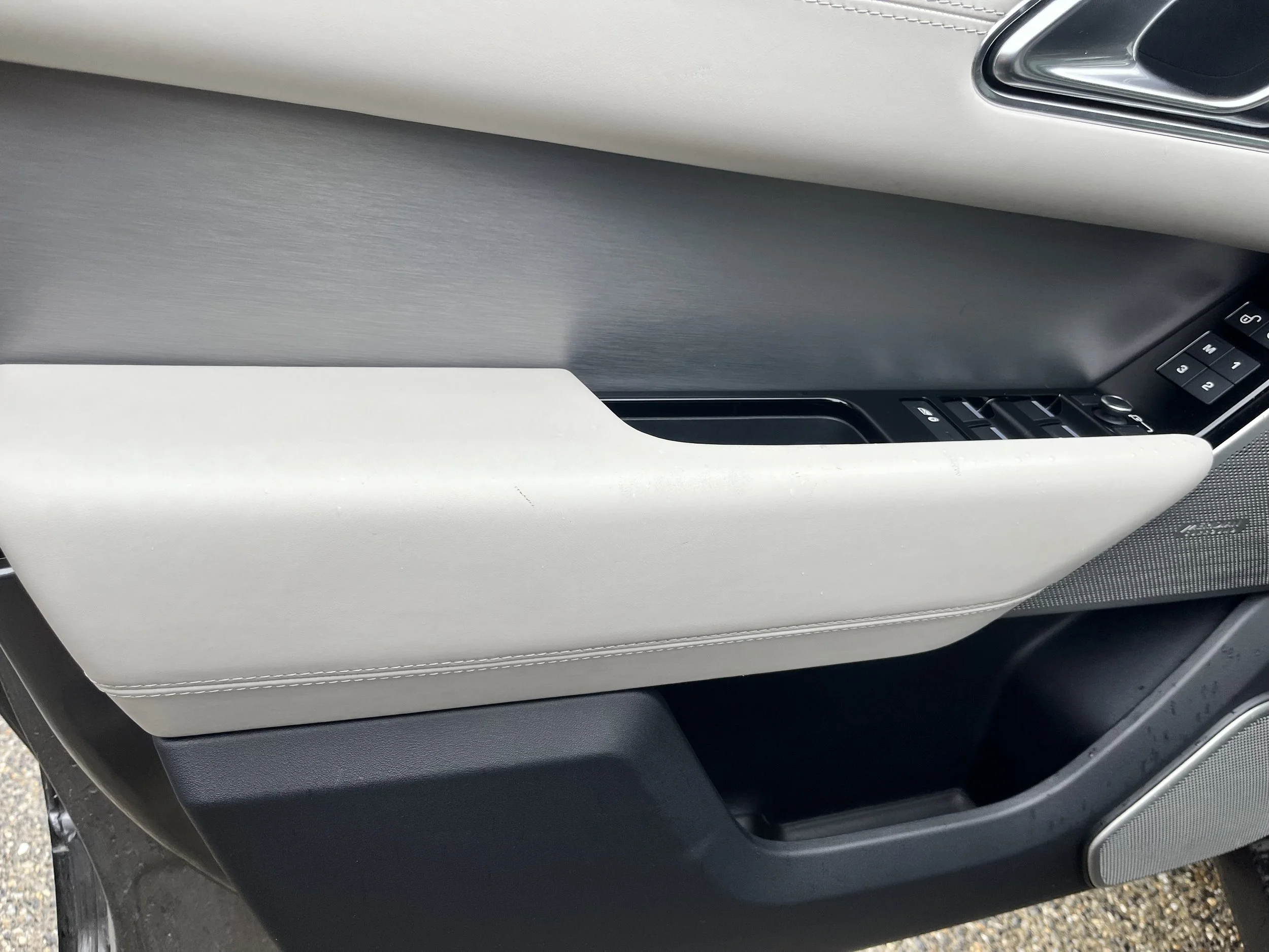 Close-up of a car door interior showing the door handle, window controls, and speaker.