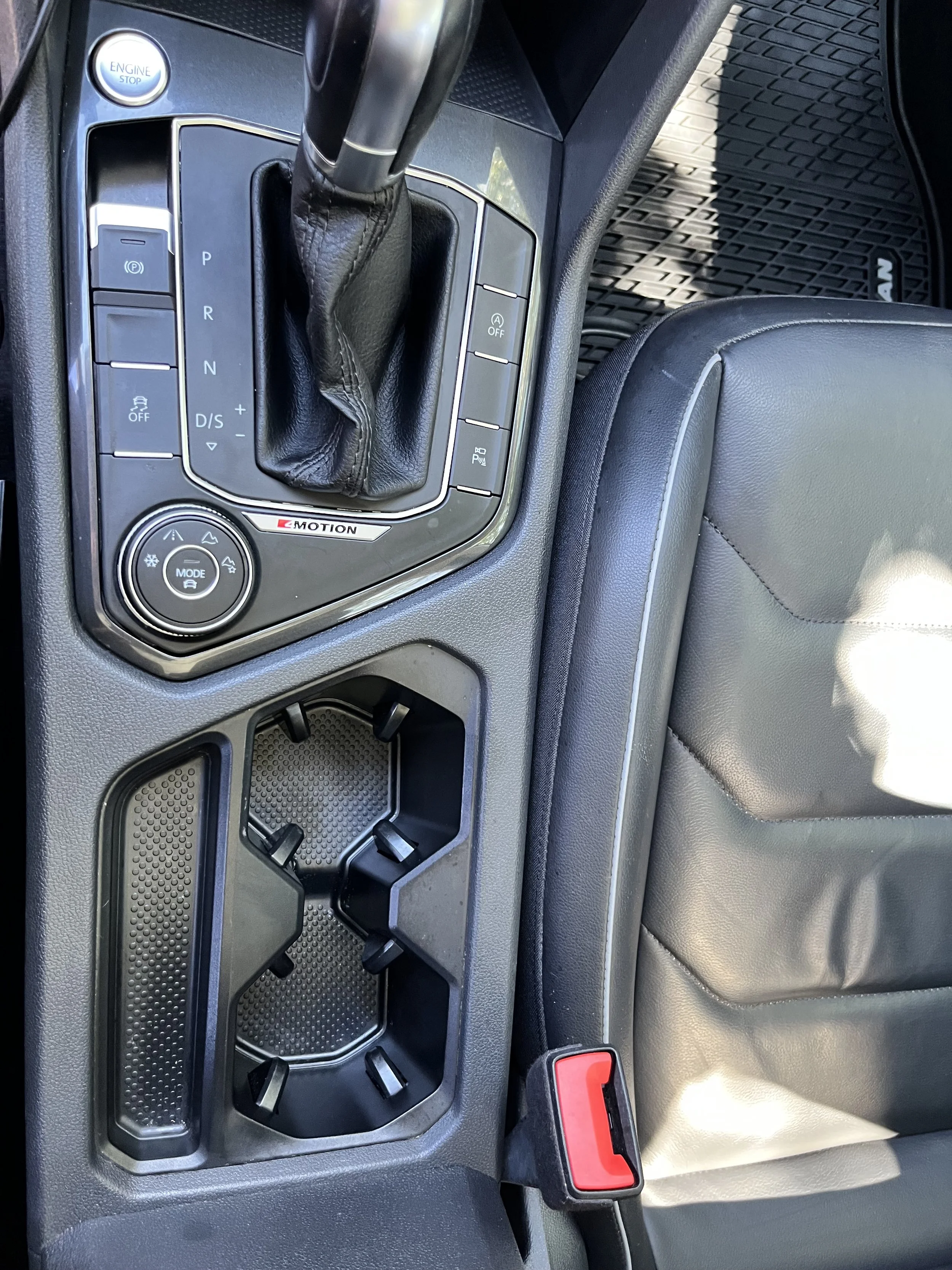 Center console of a car showing the gear shift, cup holders, and various control buttons.