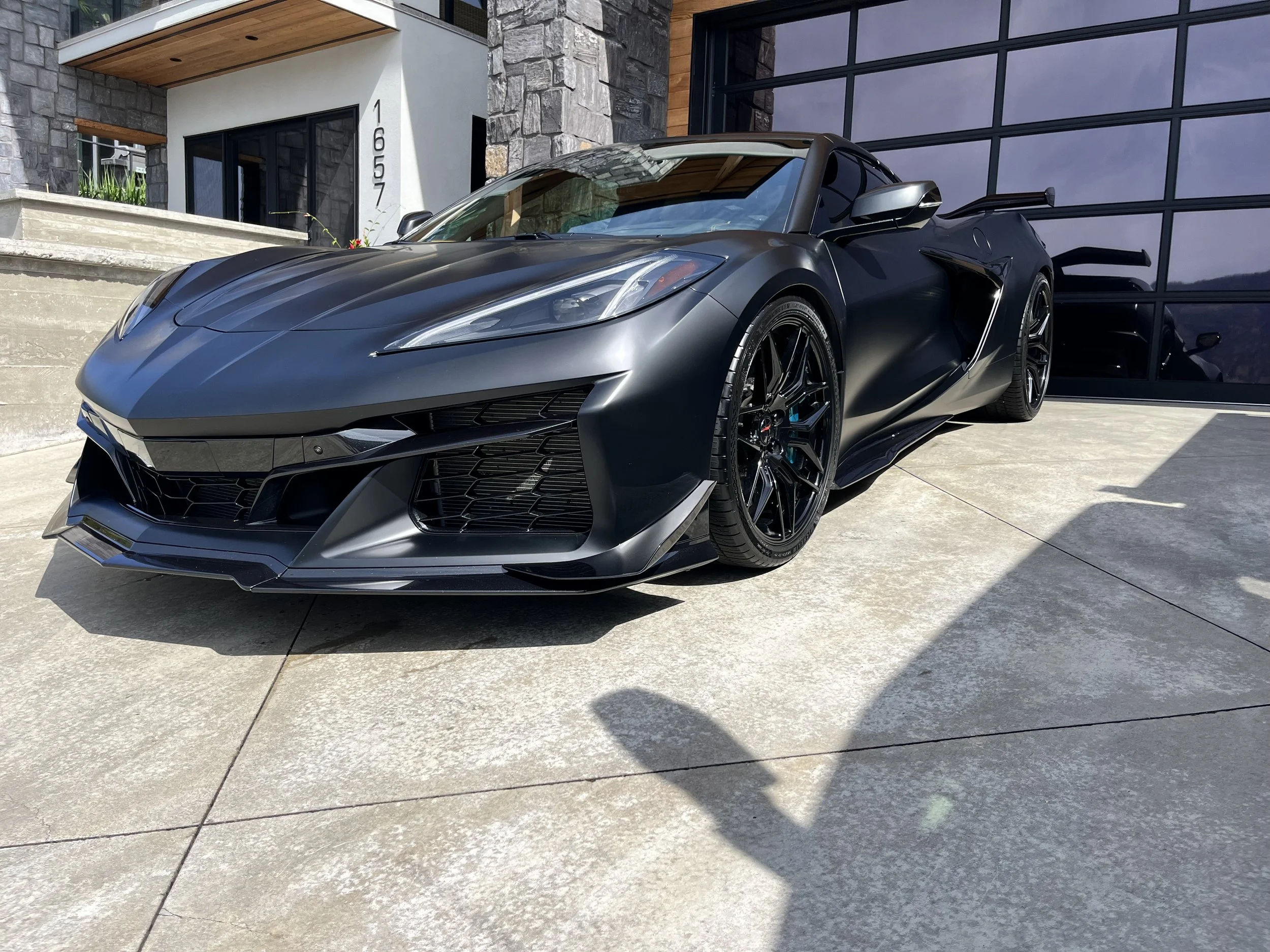 Rear view of a blue Audi RS3 parked on a paved area with greenery in the background.