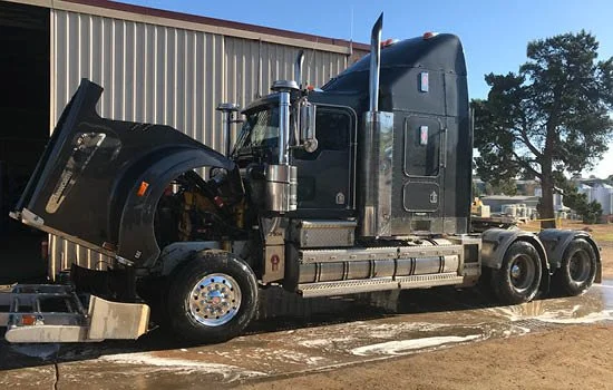 Semi-truck with hood open parked outside the Kapunda Diesel Repair workshop on a sunny day.