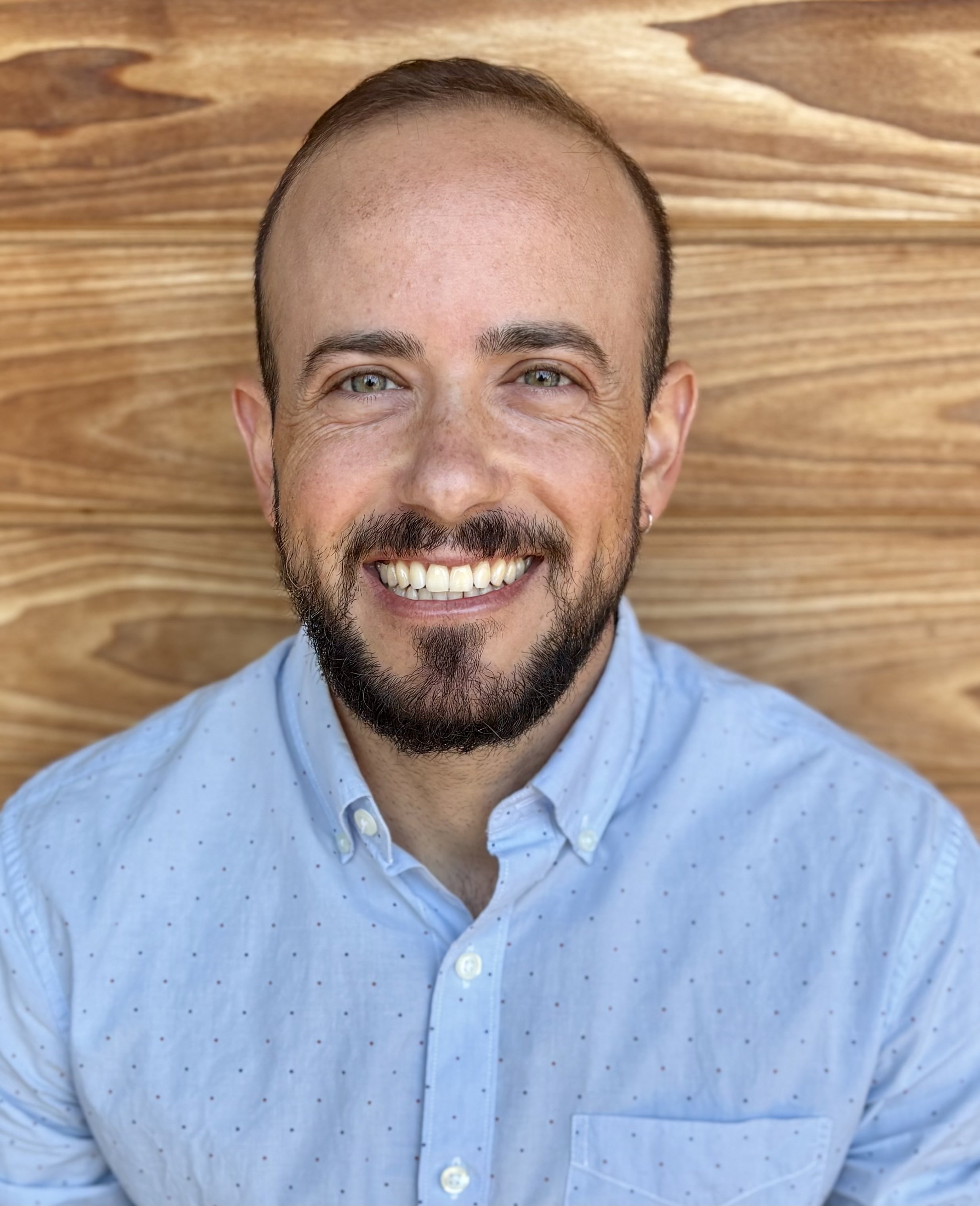 Person with beard in blue shirt sitting