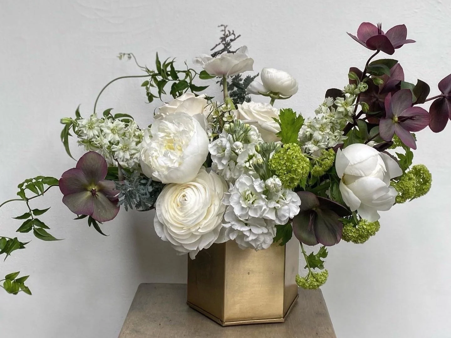 white flowers with notes of green and deep purple flowers in bronze geometric vase