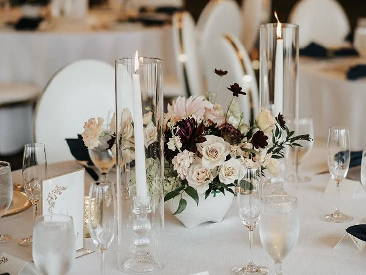Elegant event table with floral centerpiece, tall candles, and glassware.