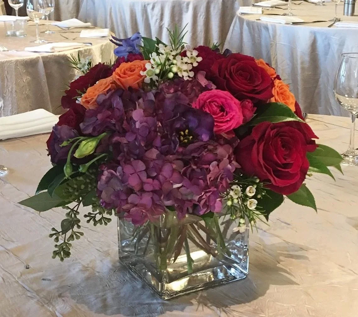 moody dark red, purple and pink flowers in glass cube vase