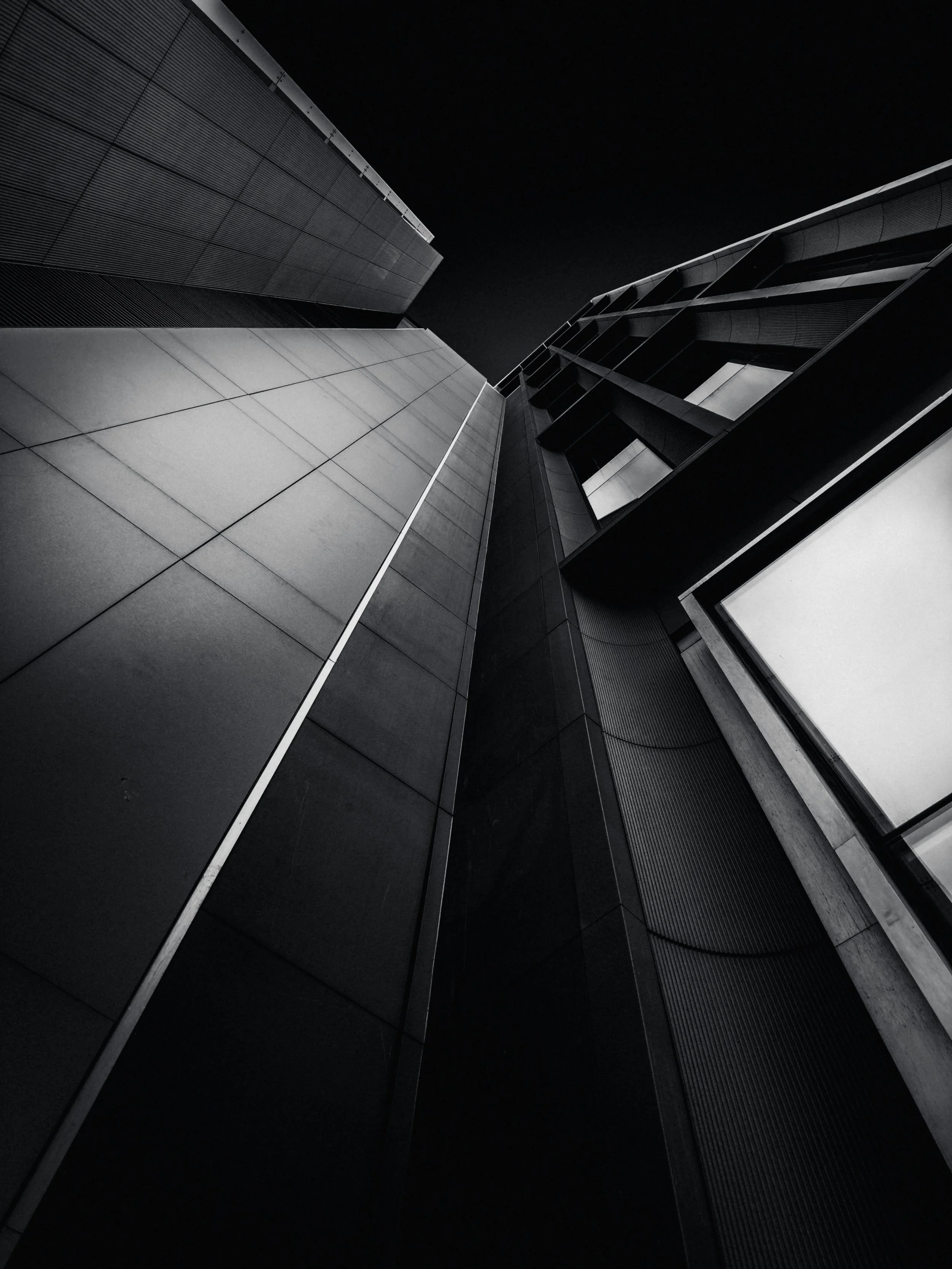 View of modern skyscraper buildings from below, black and white photograph, looking up at the towering structures.