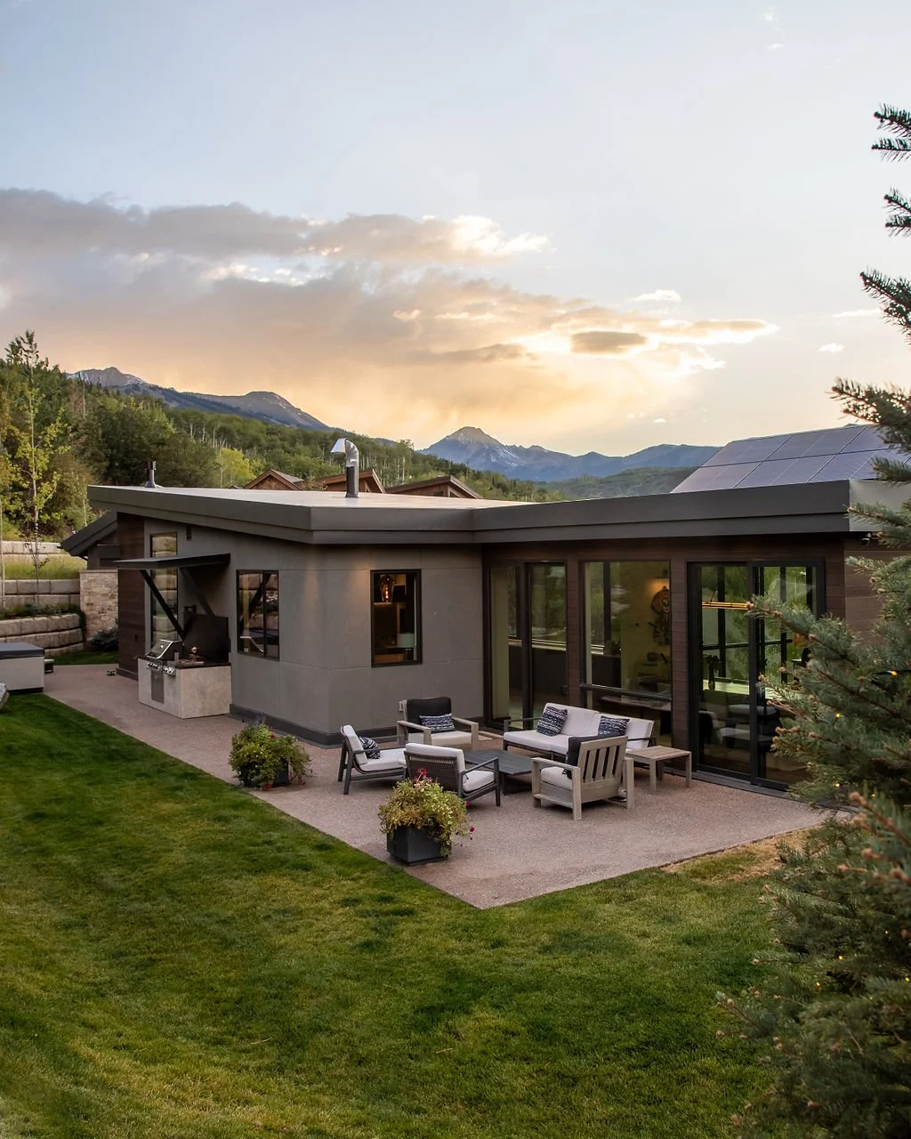 Modern house with outdoor patio, sitting area, and mountain view during sunset