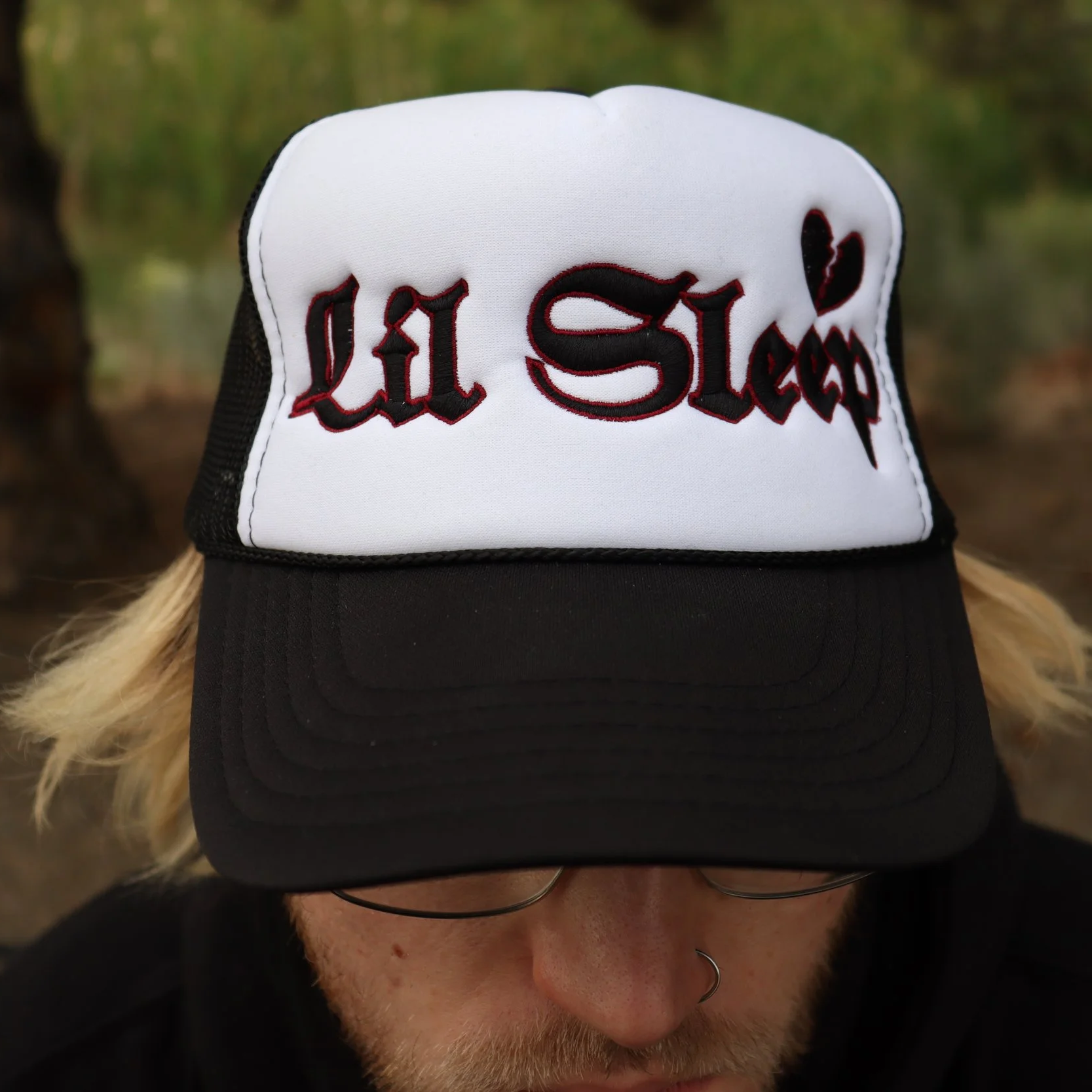 white panel trucker hat with Lil Sleep logo and a broken heart above in black it is all embroidered