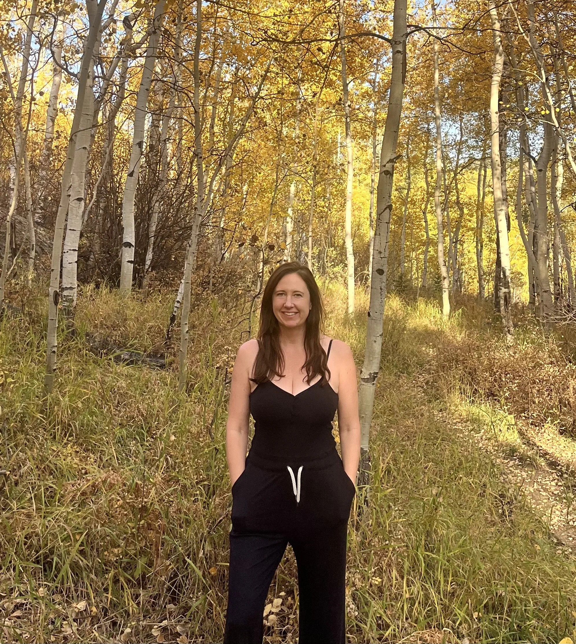 Person standing in a forest with beautiful fall foliage
