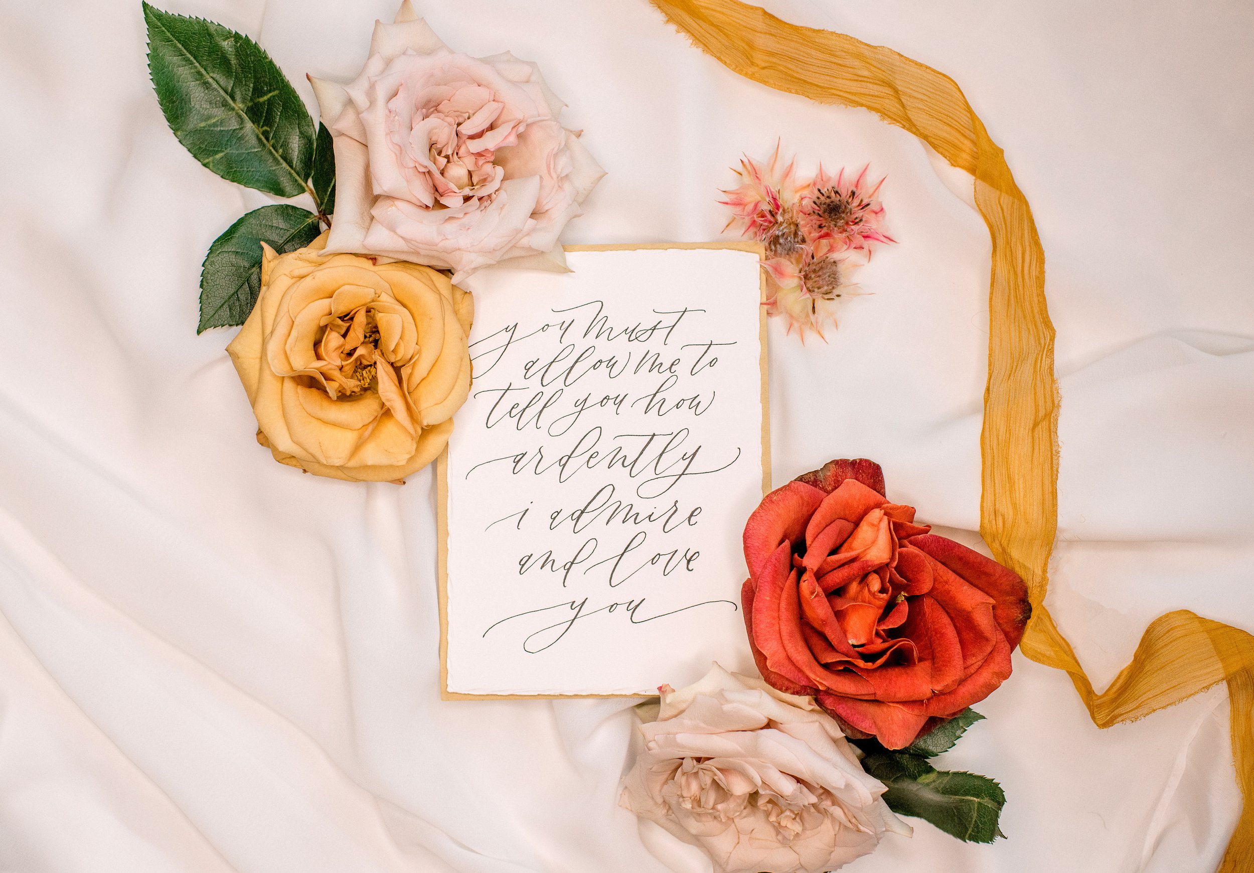 Scripted Calling, Pensacola Florida Calligraphy & Engraving - hand lettered, calligraphy, Handwritten quote, letter surrounded by roses on fabric background, flat lay