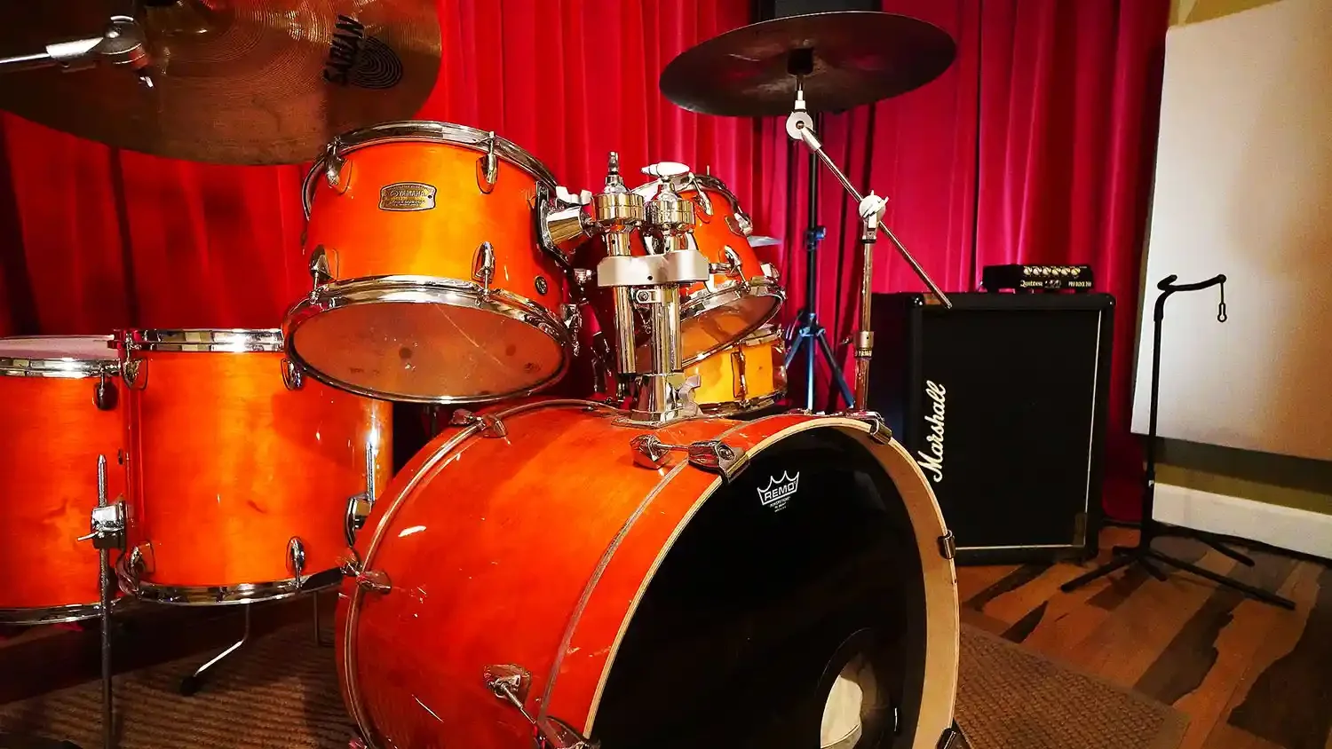 Batterie de musique orange devant amplificateurs Marshall