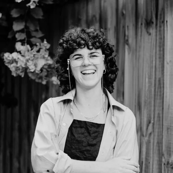 Producer Bron Belcher, laughing in front of a wall of flowers