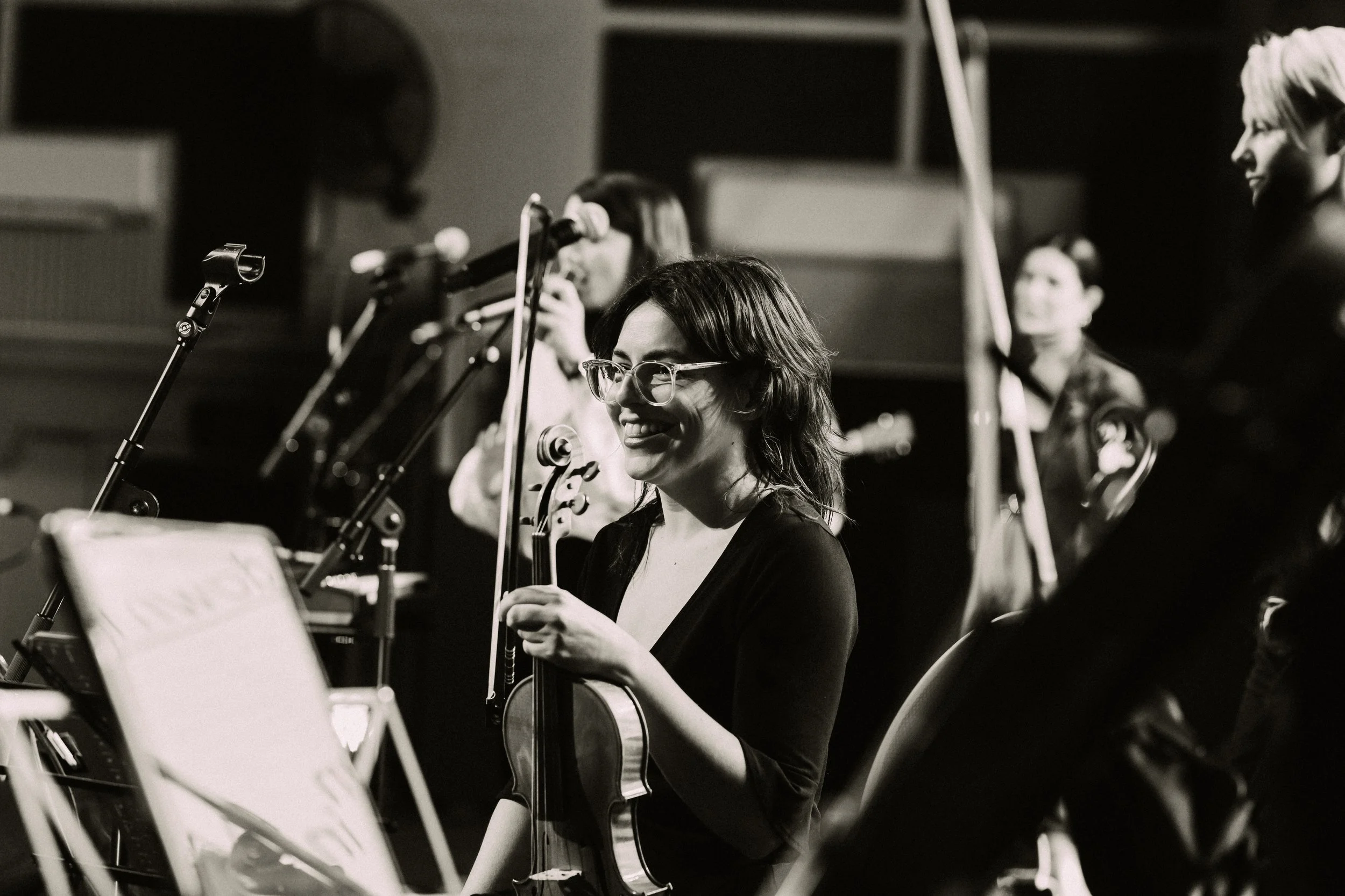 Put It On founder Madeleine Jevons, smiling holding her violin at a community event