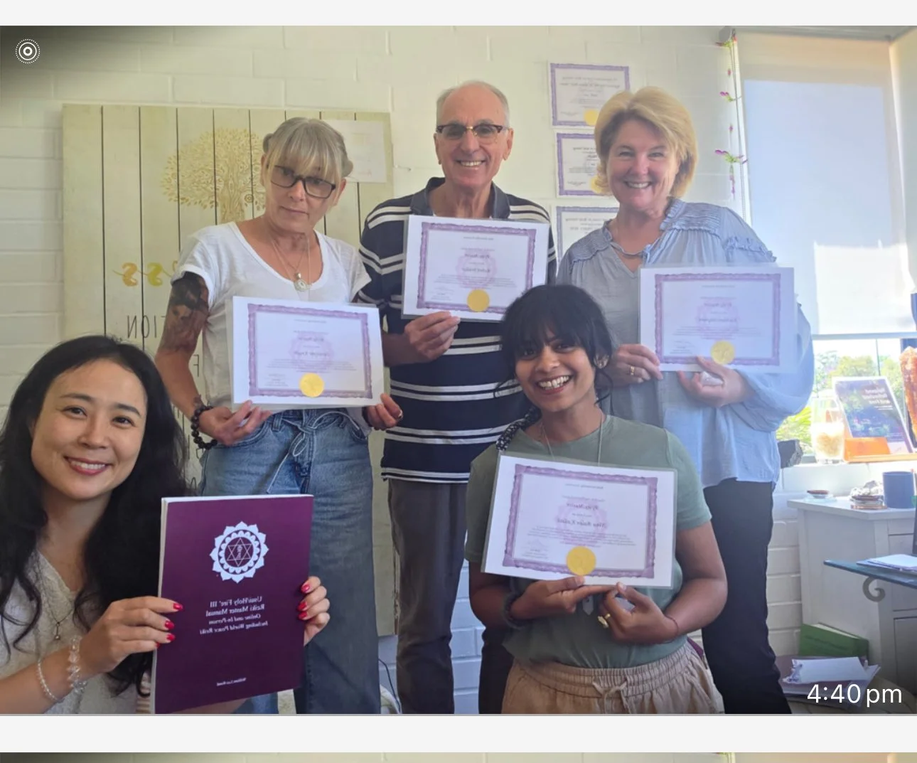 Group of five women and one man proudly holding certificates indoors, celebrating achievement, with smiling faces.