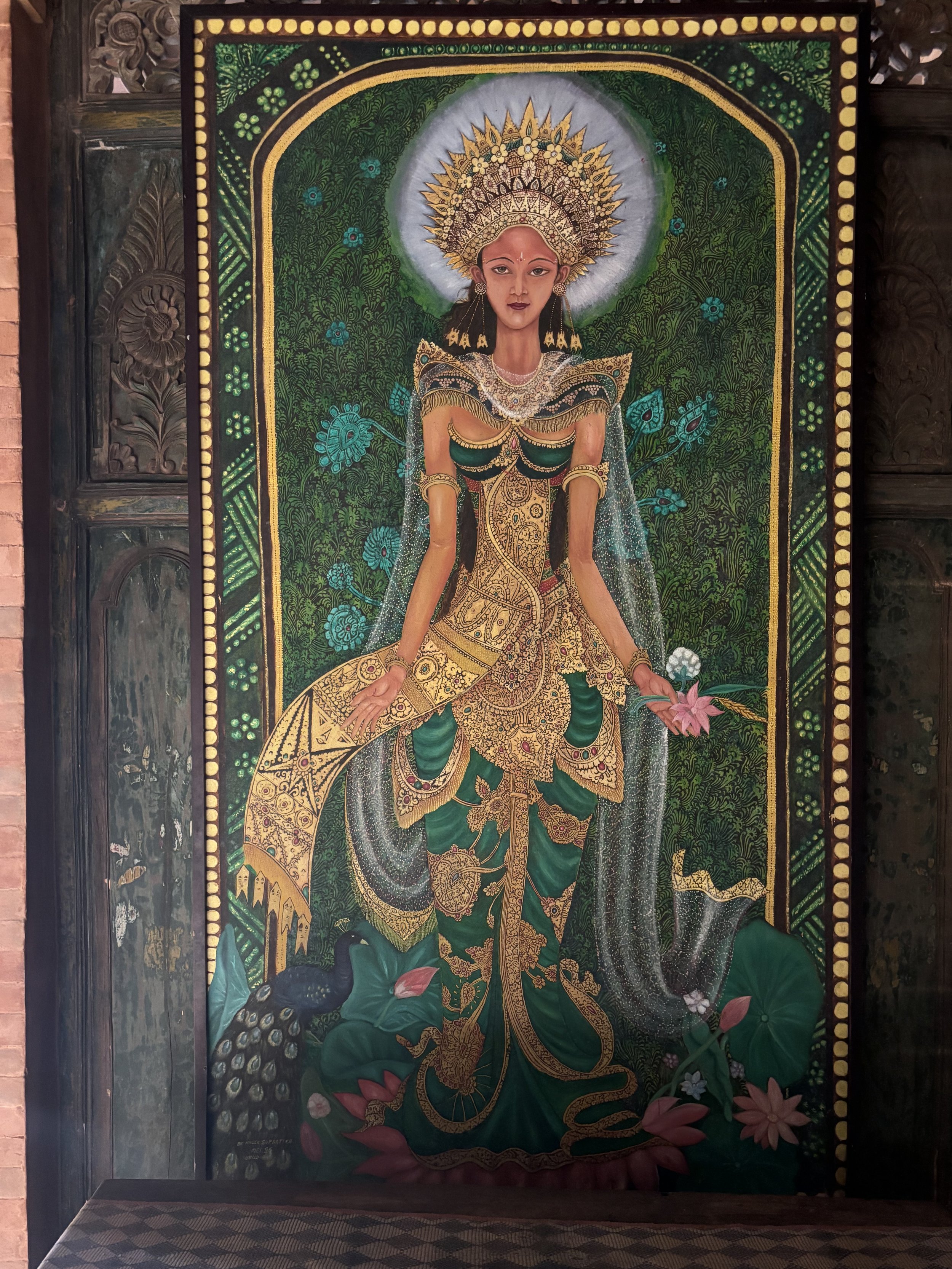 Colorful traditional painting of a woman wearing ornate jewelry and a crown, surrounded by floral patterns.
