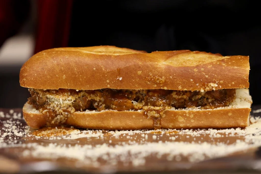 A close-up of a meatball sub sandwich with toasted bread, meatballs, marinara sauce, and parmigan cheese.