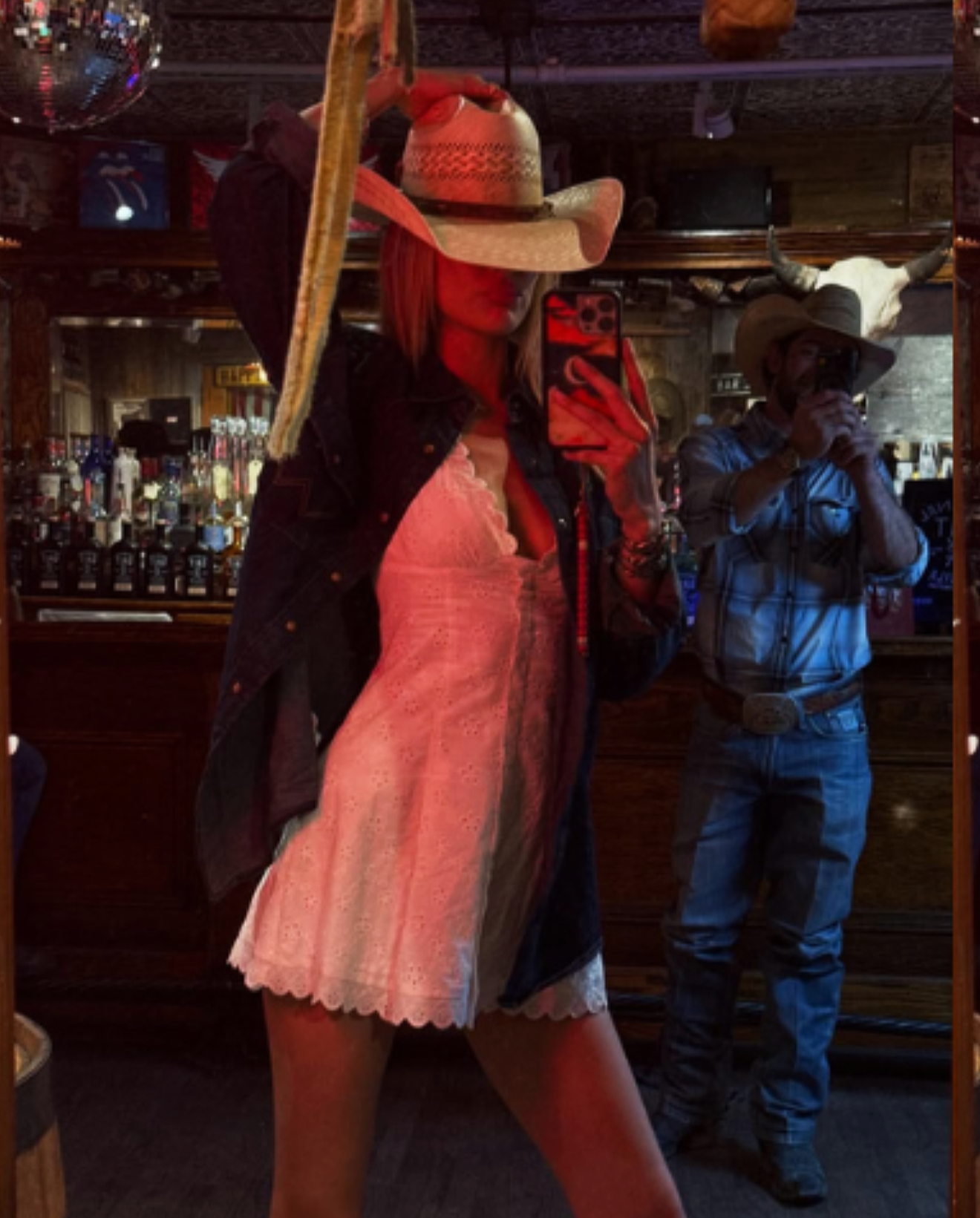 Bella Hadid mirror selfie in a cowboy hat, white eyelet mini dress and denim jacket at a western bar