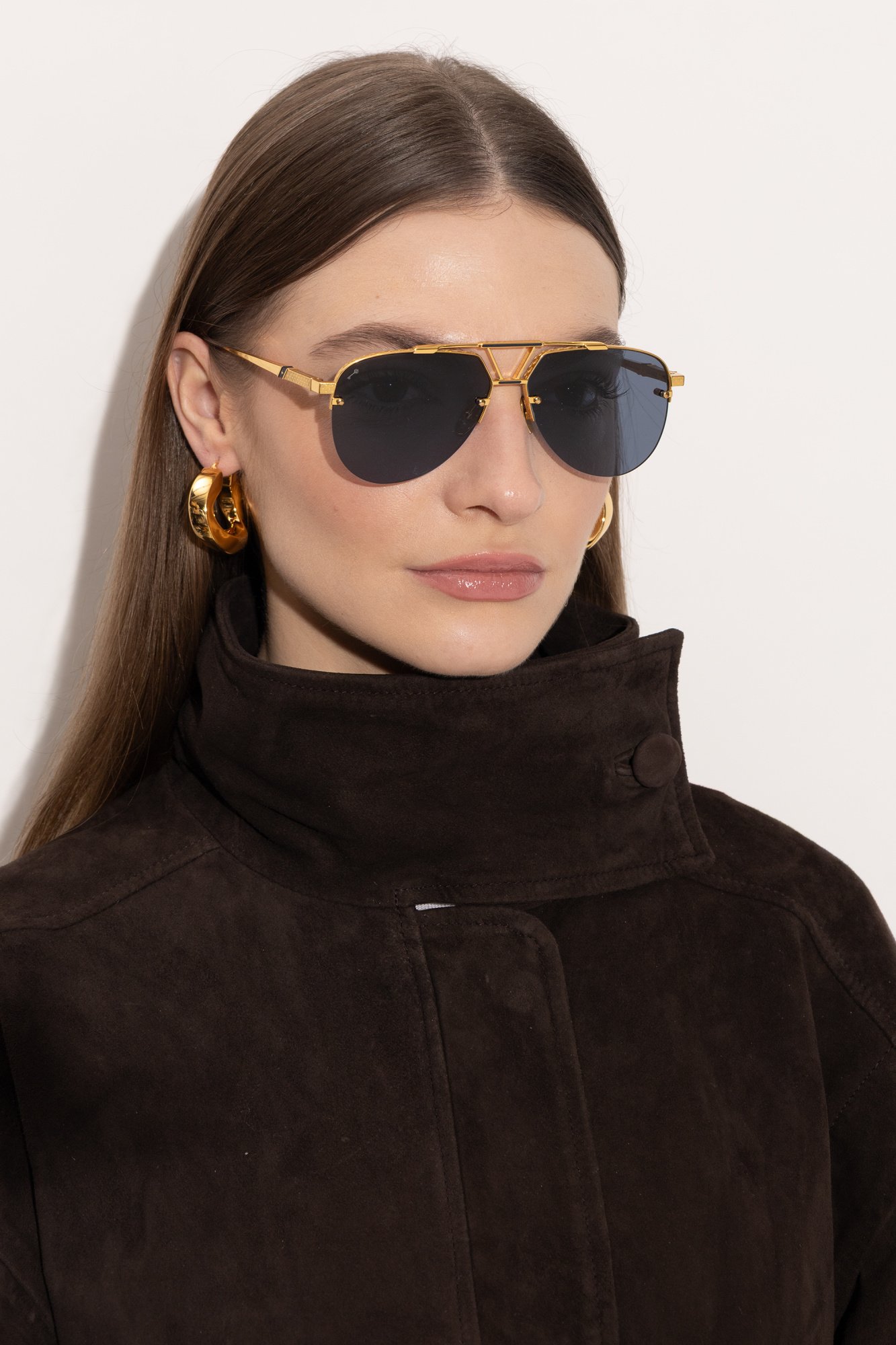 Model in Leisure Society Bandini 18K gold aviator sunglasses and brown suede coat