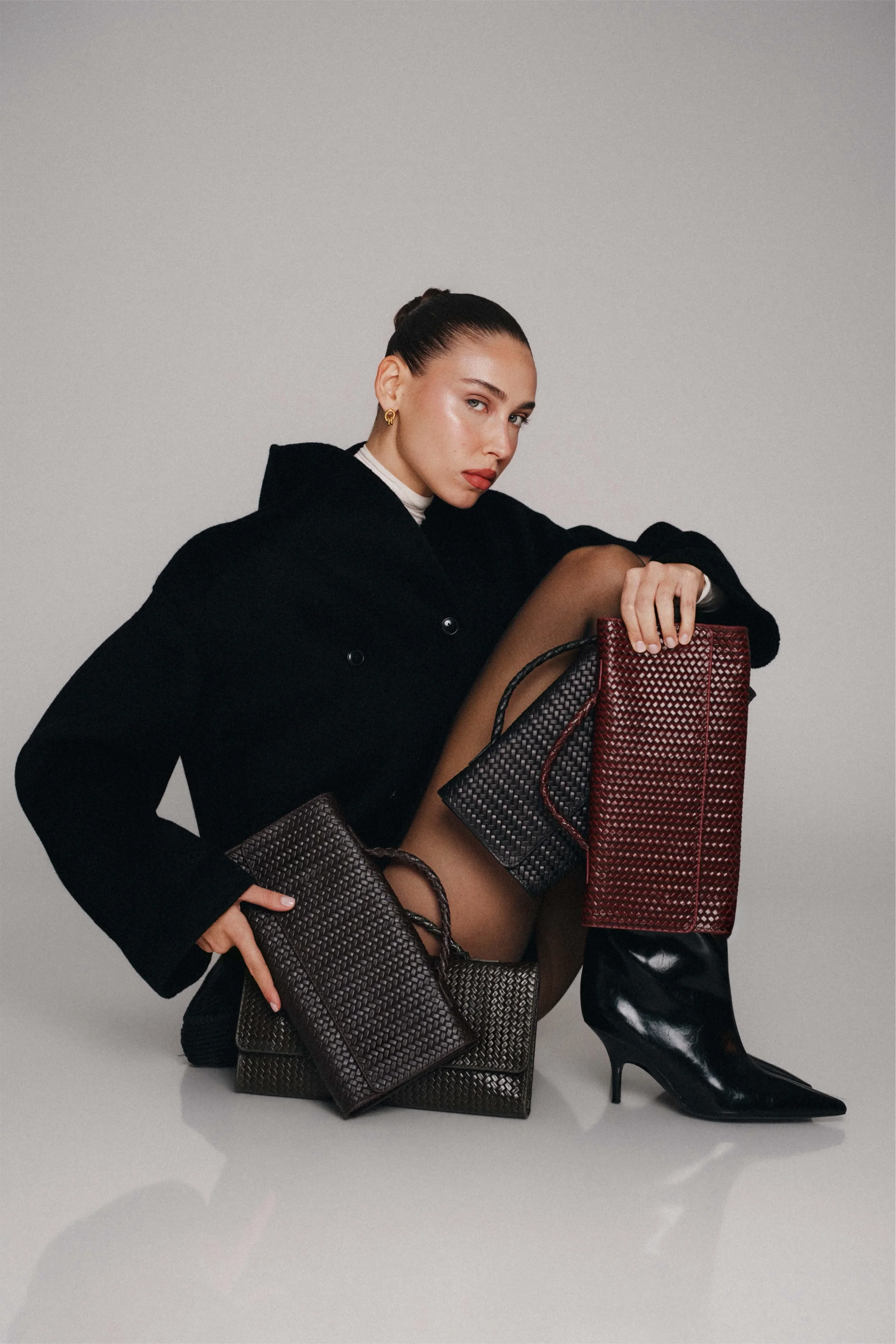Model in a black coat with three Noam Hazan woven leather bags, Noam Hazan campaign