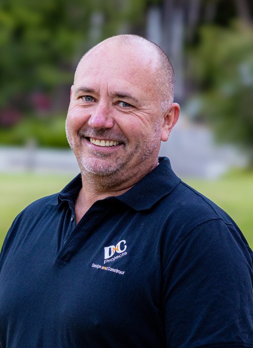 Smiling man in a black polo shirt outdoors