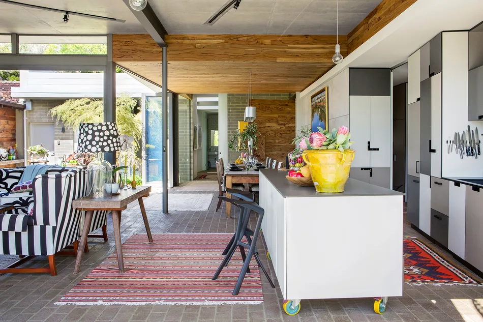 Modern kitchen and dining area with colorful decor, striped chairs, potted plants, and contemporary design elements.