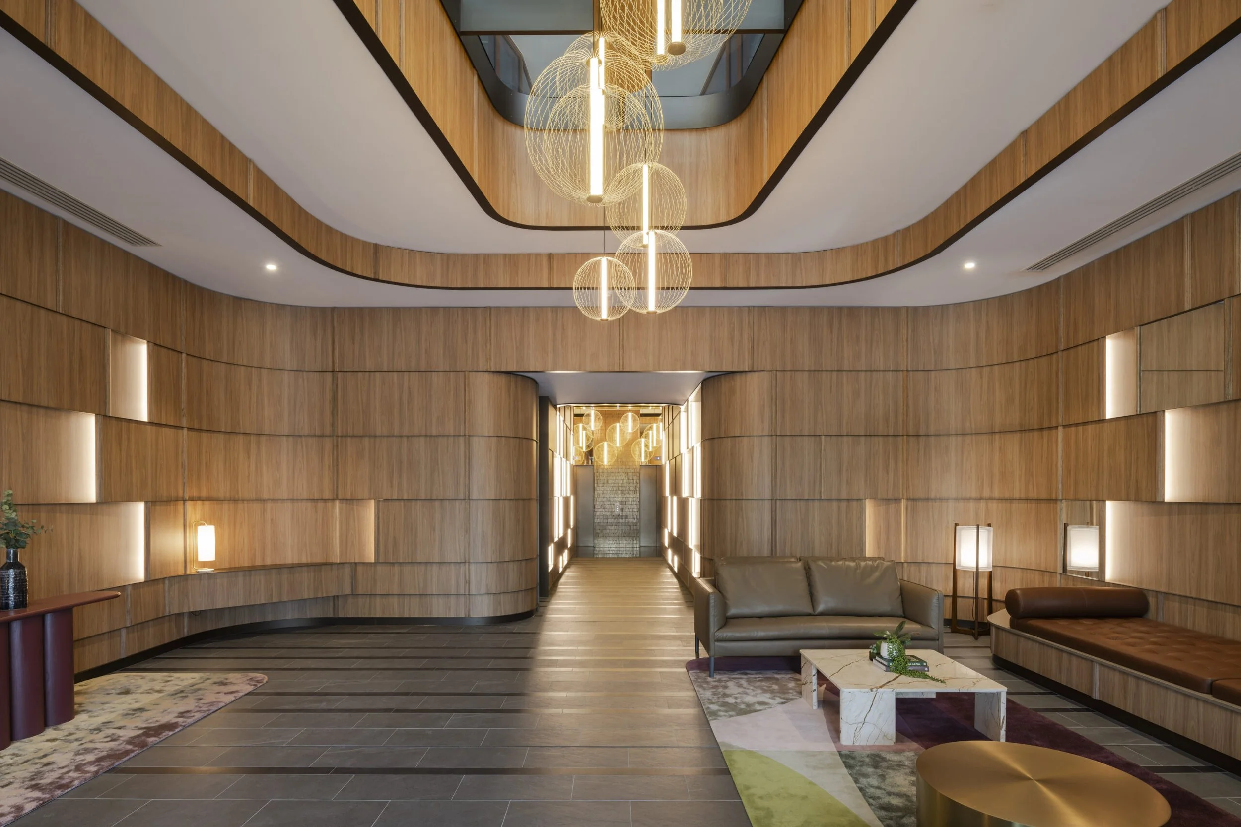 Modern lobby with wooden panel walls, contemporary lighting fixtures, and stylish furniture.