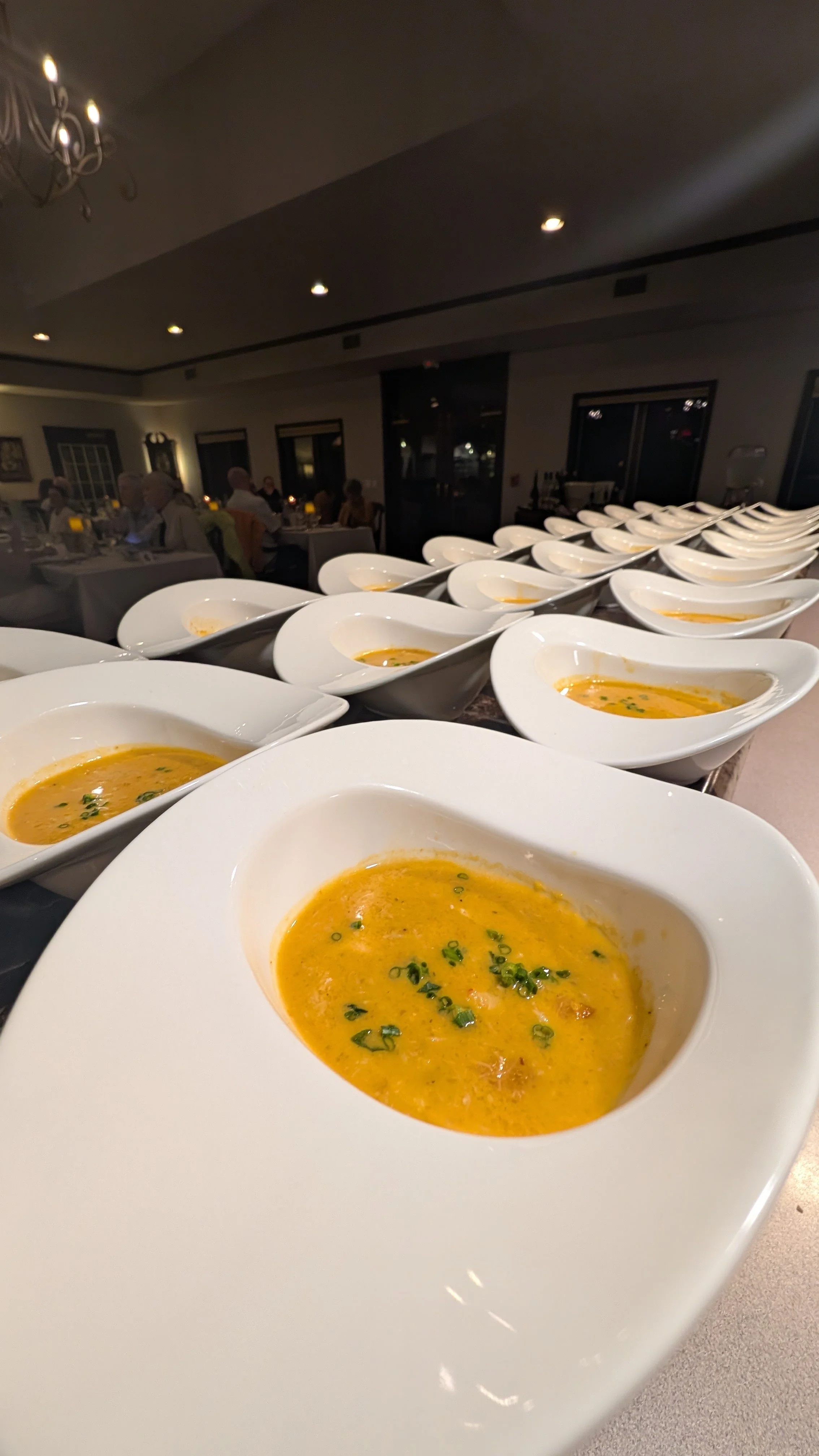 Multiple bowls of creamy soup garnished with herbs in a restaurant setting.