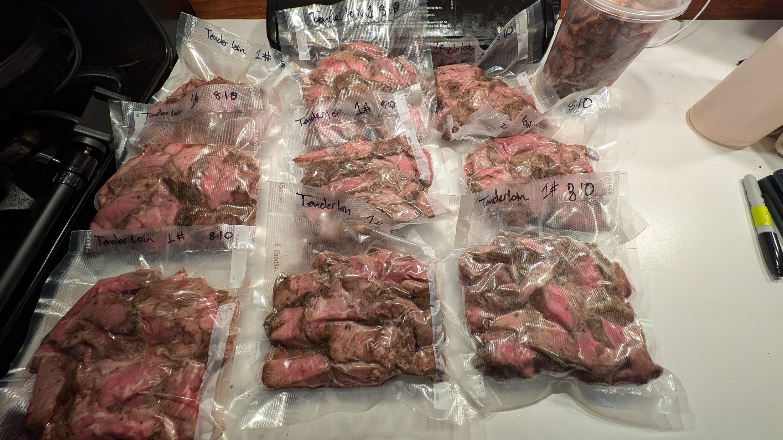 Vacuum-sealed packages of sliced beef tenderloin labeled with weight and date on a white countertop.
