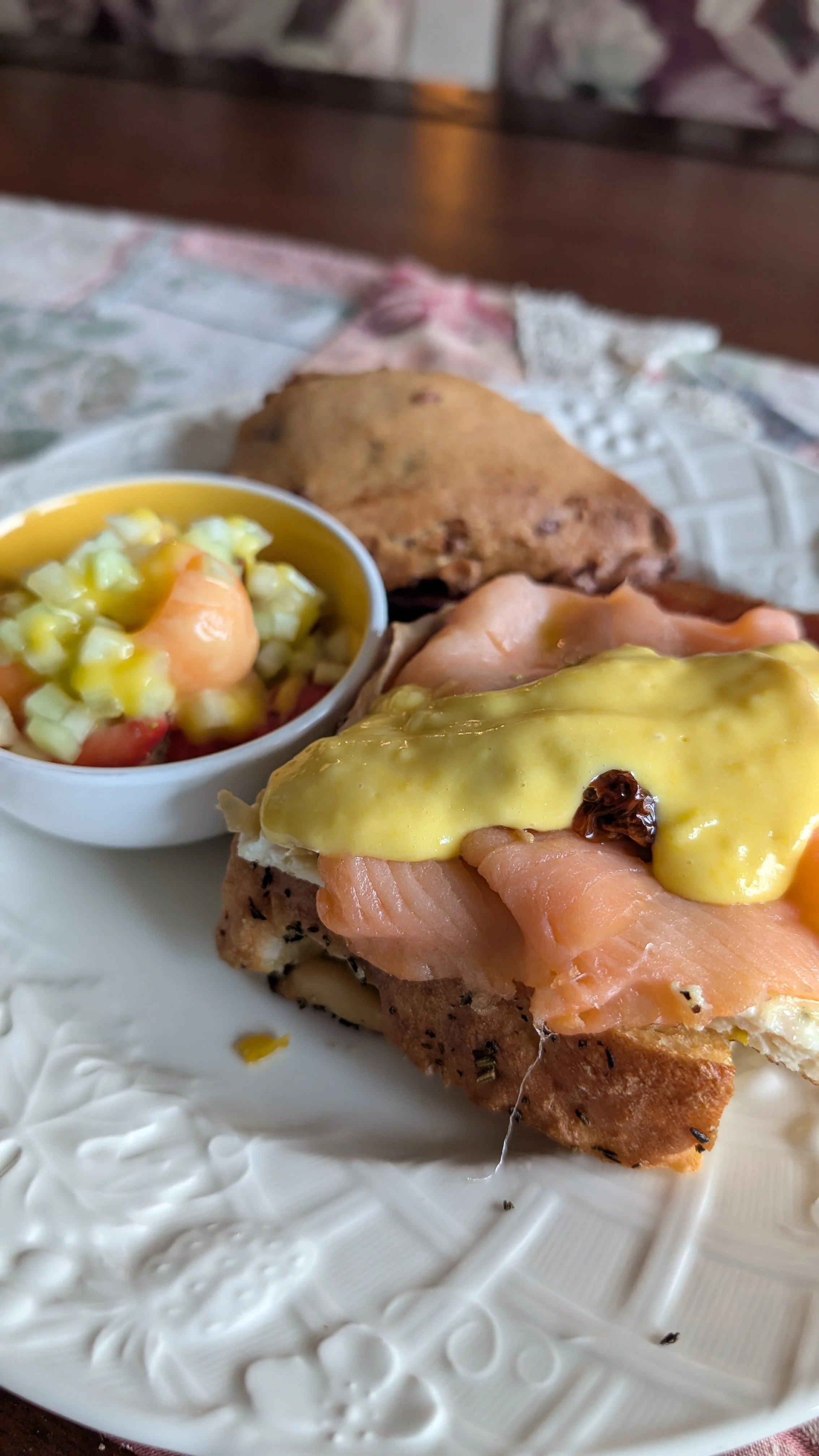 Plate with smoked salmon on bread topped with mustard sauce, a small bowl of fruit salad, and a scone.