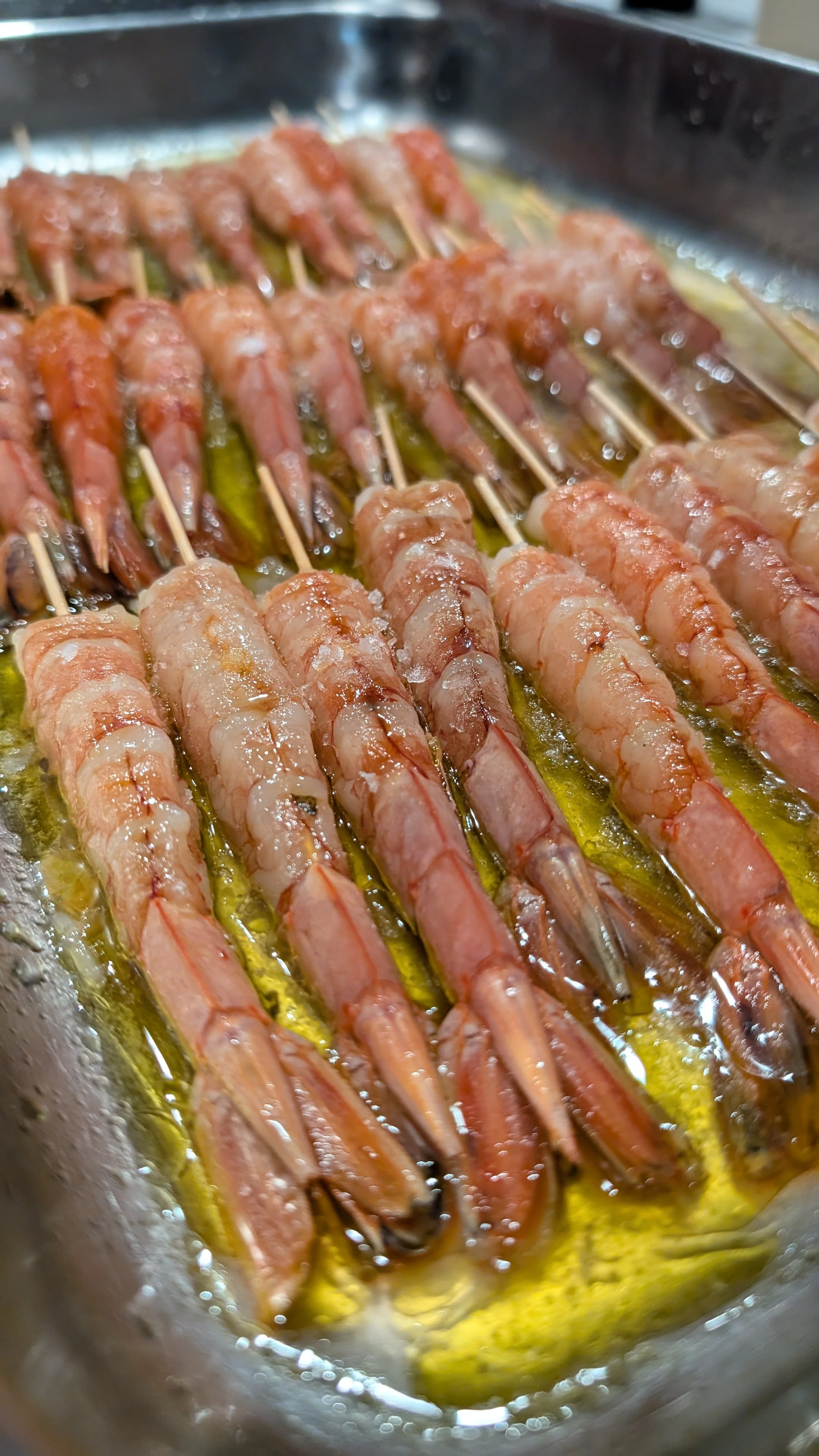 Skewered prawns marinating in olive oil