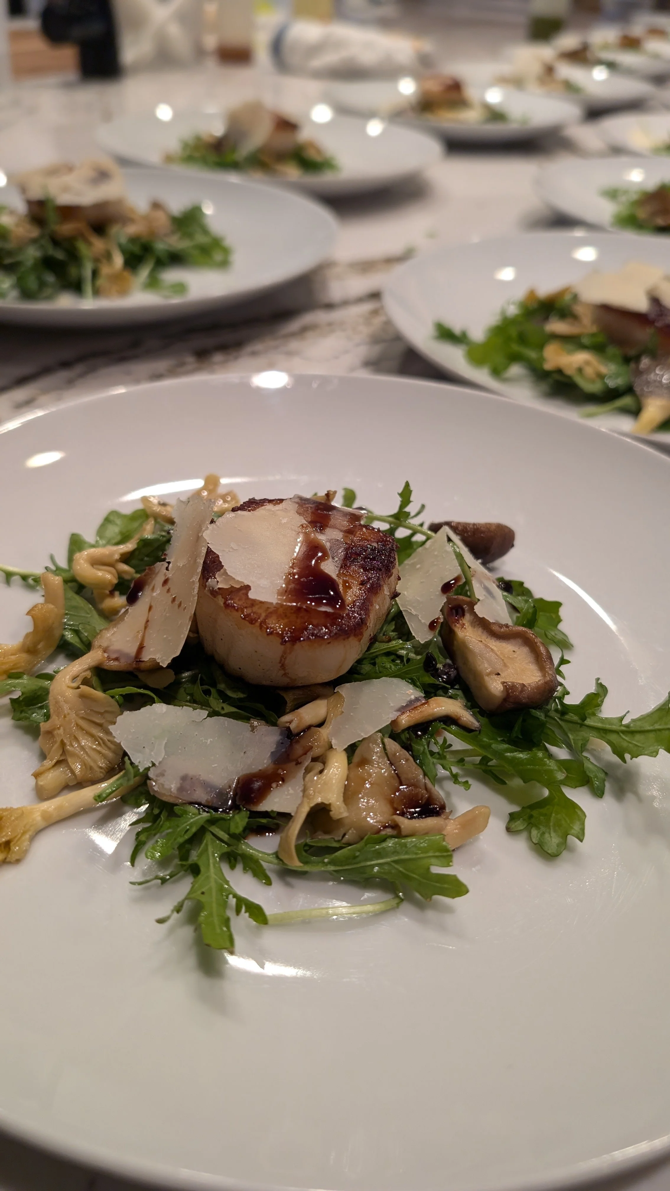 Seared scallop on arugula with mushrooms and Parmesan, drizzled with balsamic glaze.
