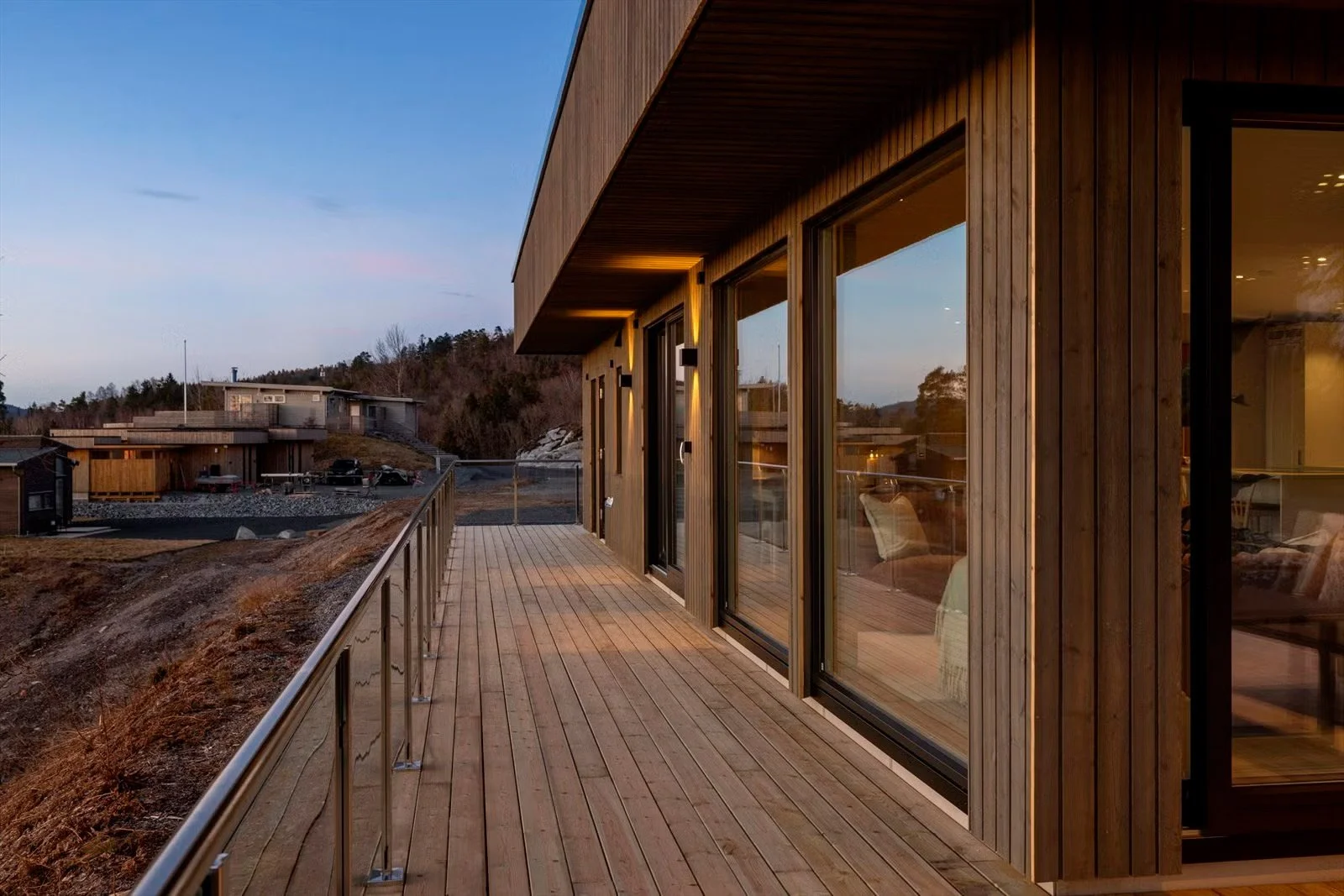 Fasadebilde som viser store vinduer og utebelysning.