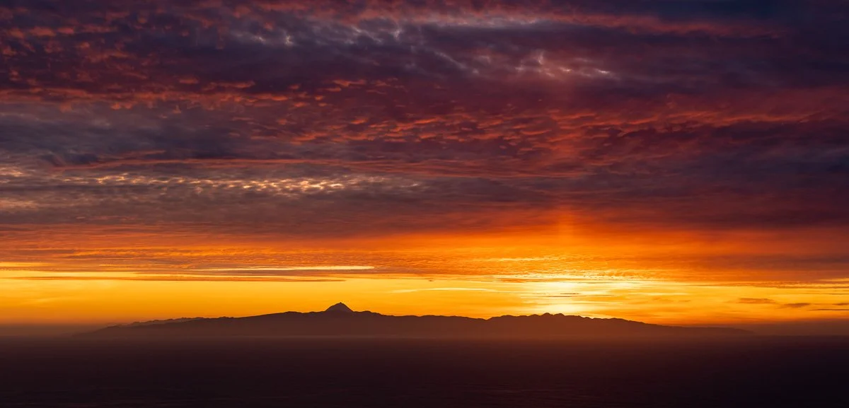 Sunset over a mountain range with colorful sky and clouds.