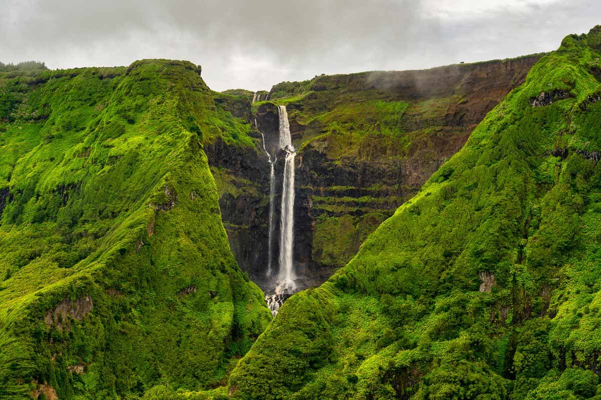 A scenic view of lush green mountains with a waterfall cascading down the center.