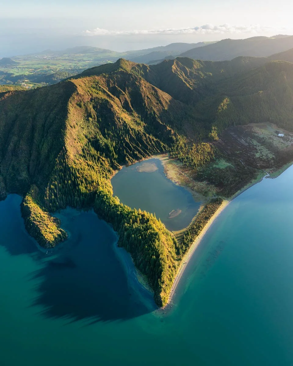  aerial view of a coastal mountain landscape with a mountain, forested areas, and a shoreline