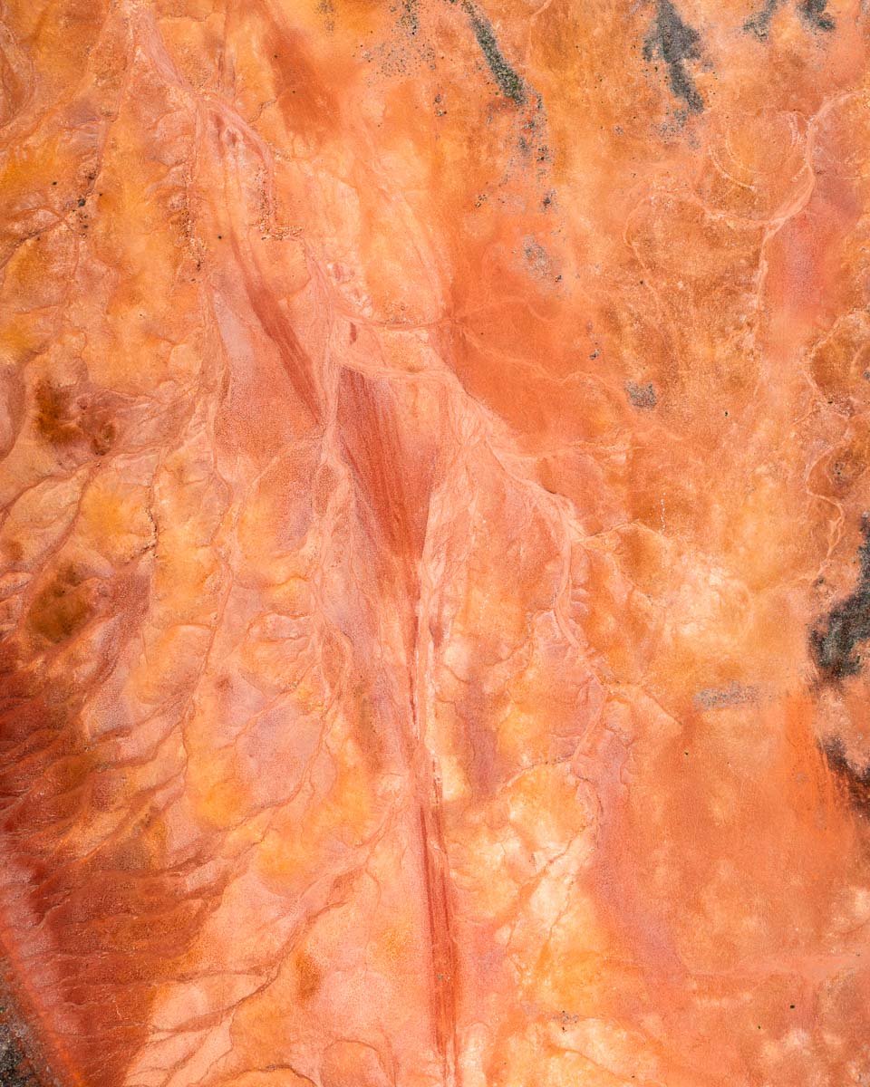 Close-up of a textured, reddish-orange stone surface with natural veins and patterns.