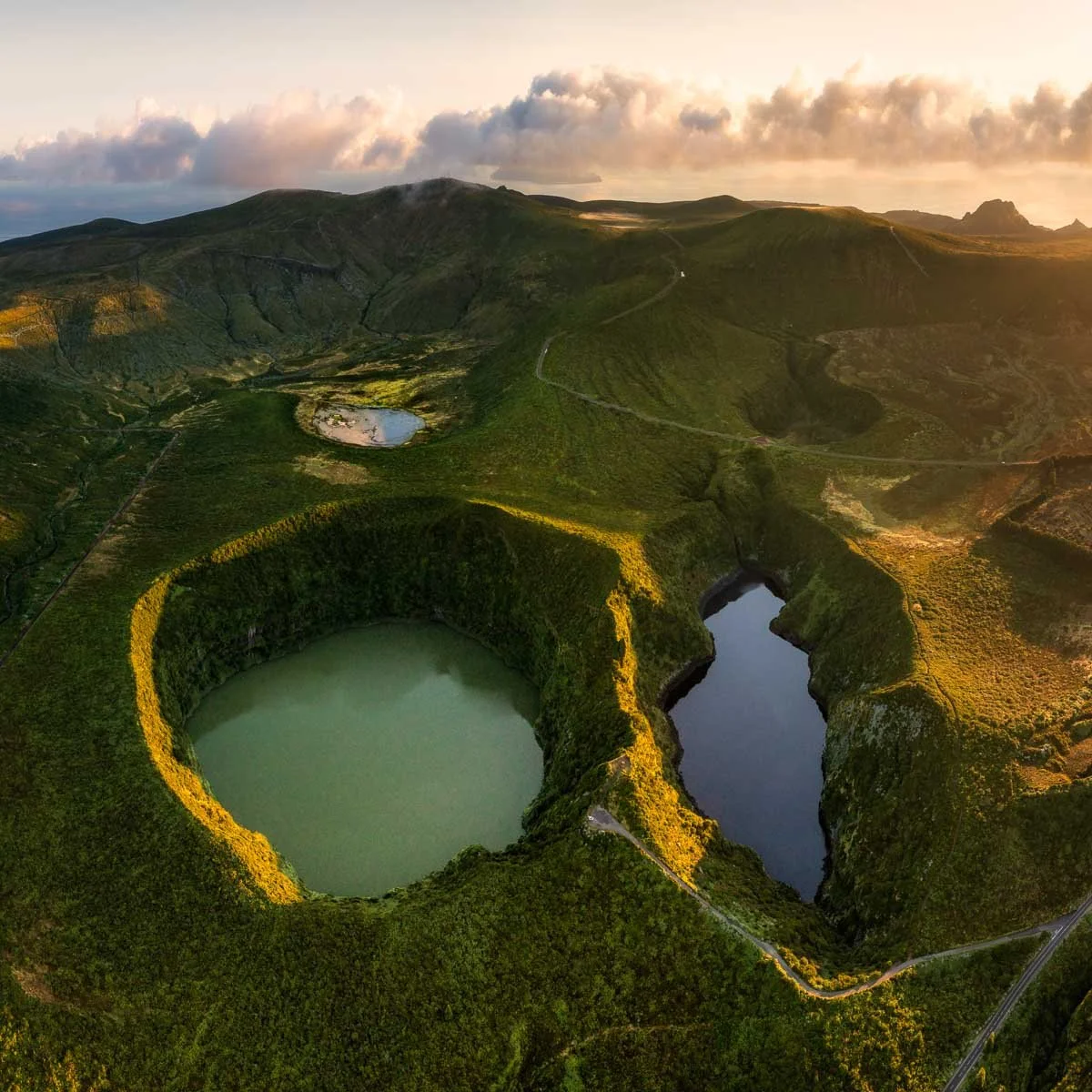 Aerial view of crater lakes and green rolling hills at sunset.