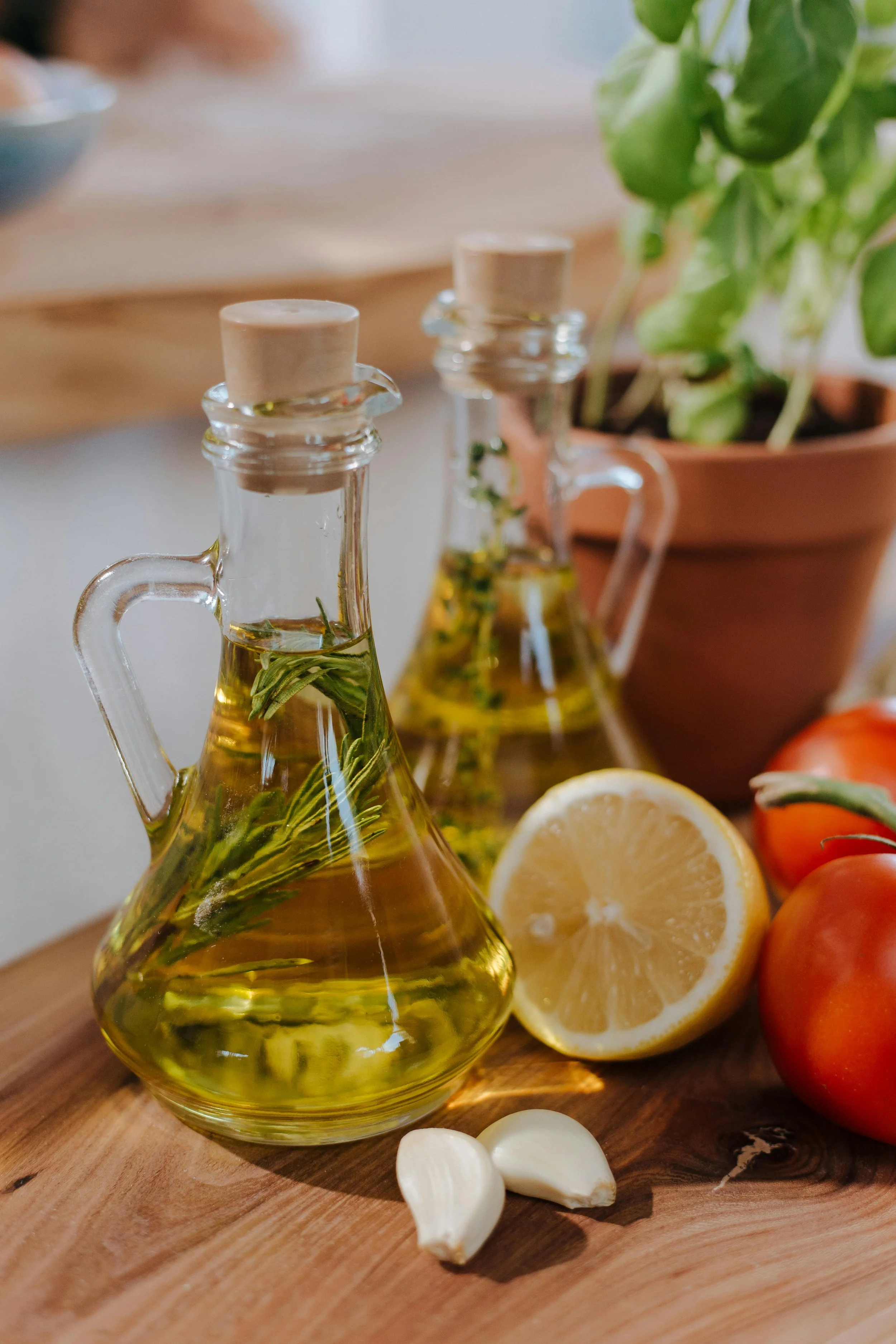 Olive oil, tomatoes, lemon, and herbs arranged on a table
