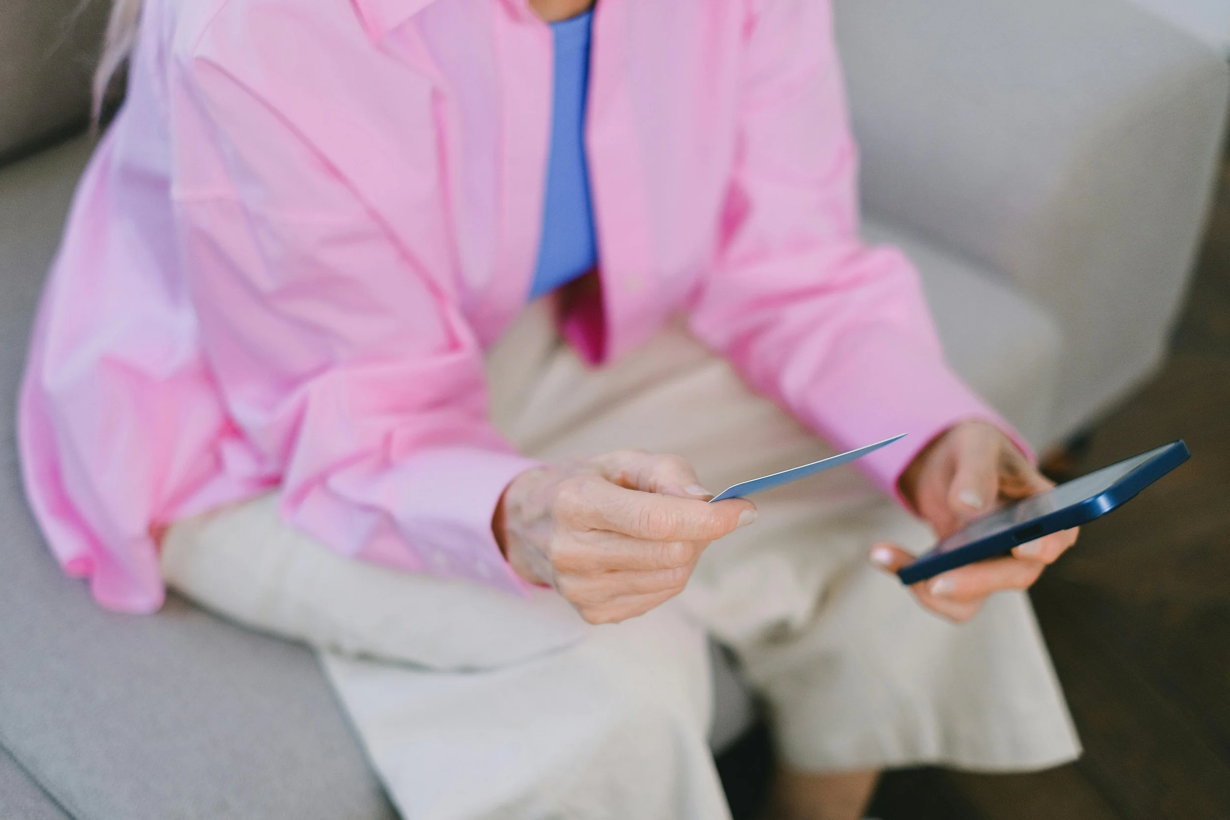 Person holding a smartphone and credit card while checking an online subscription payment.