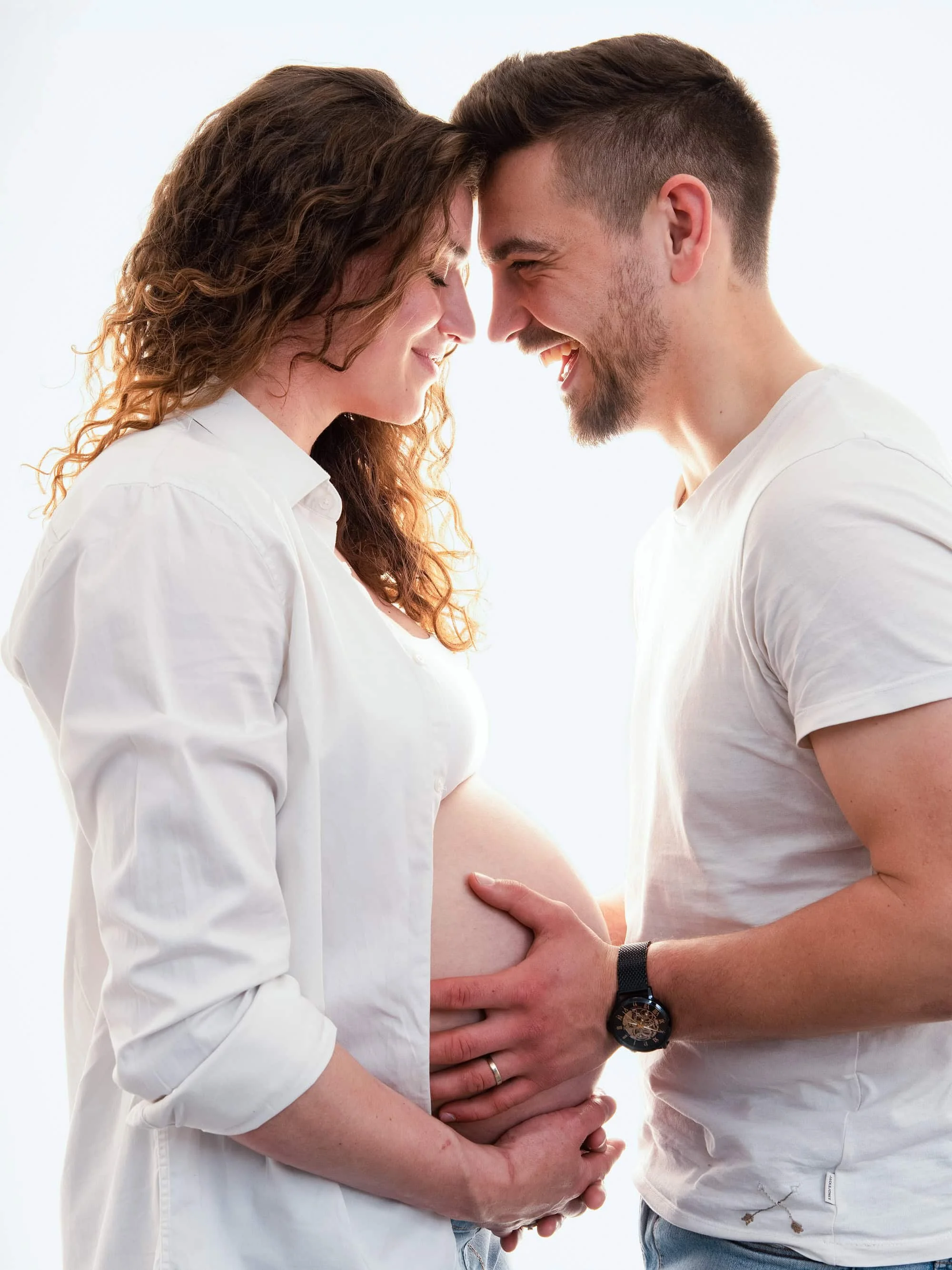 Couple de futurs parents photographié autour du ventre pendant une séance grossesse