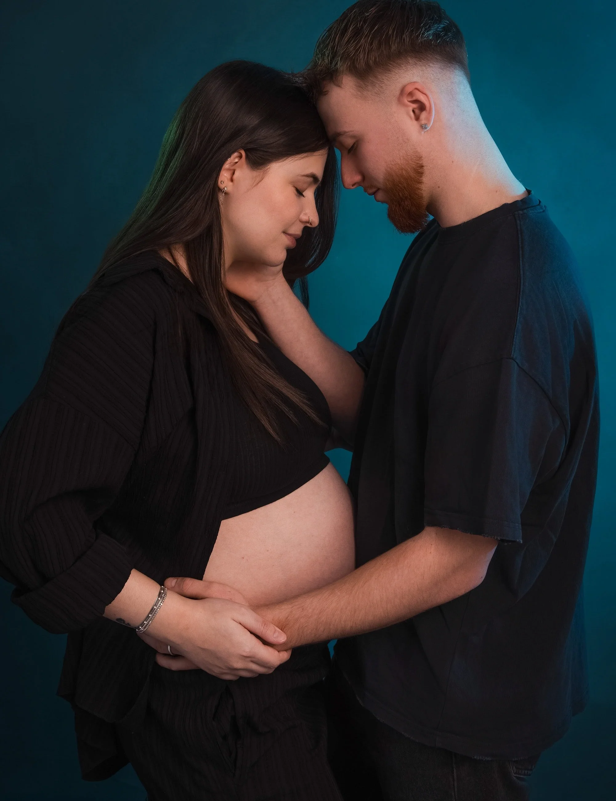 Couple attendant un enfant front contre front dans une lumière bleue au studio
