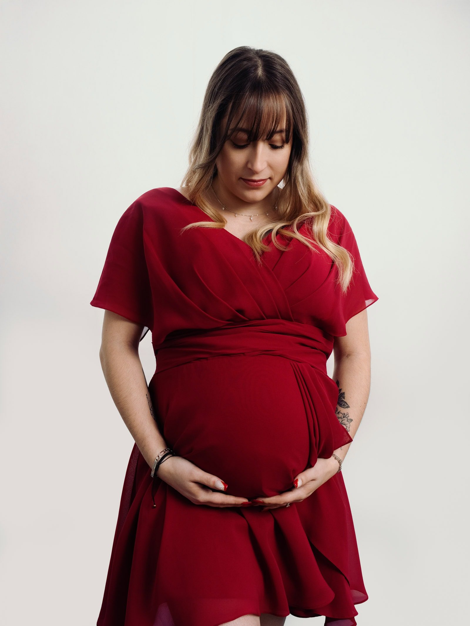 Séance photo grossesse studio Strasbourg femme enceinte robe rouge regard doux vers le ventre